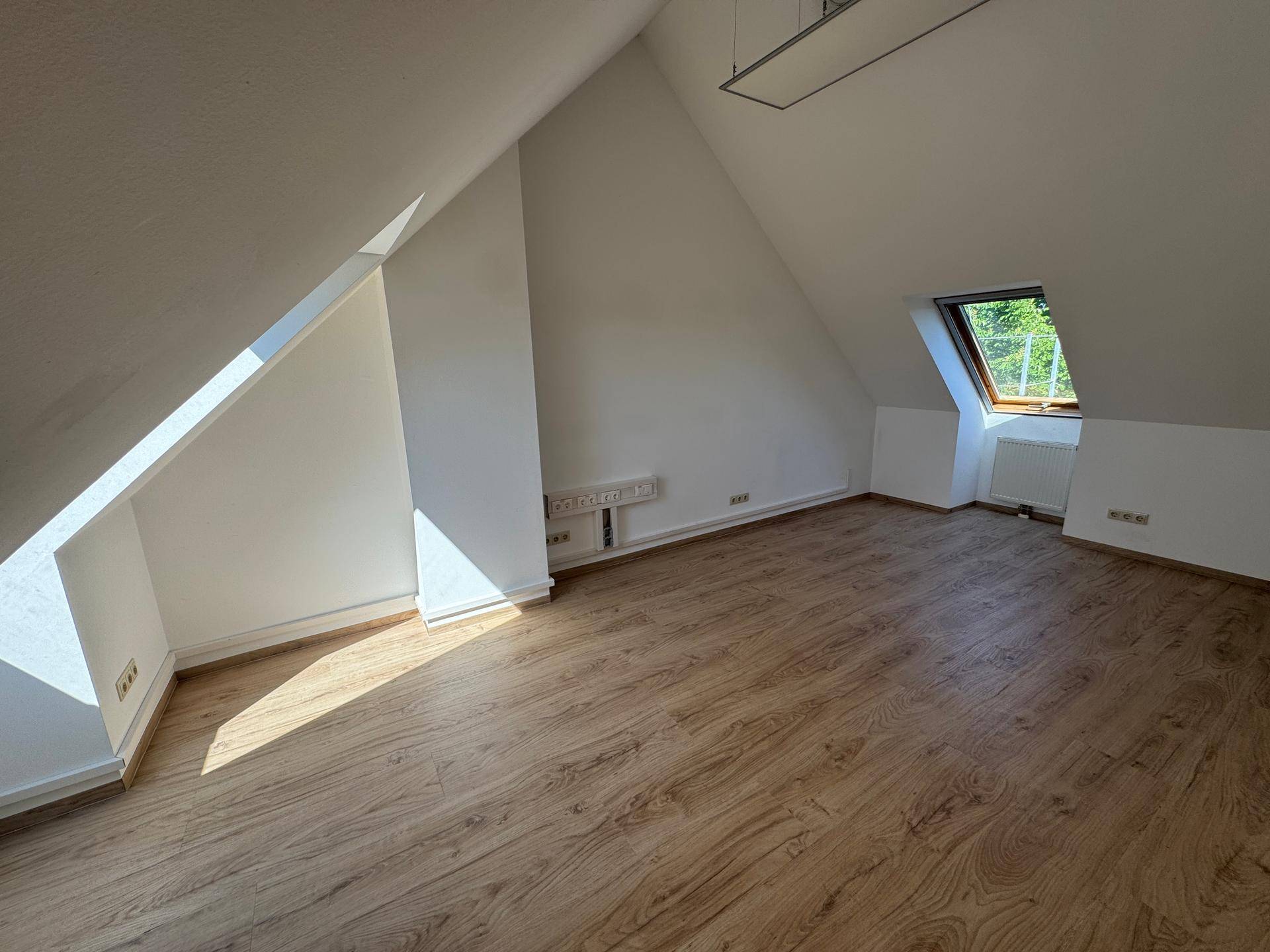 Geräumiges Zimmer mit Laminatboden, Dachschrägen und einem Dachfenster.