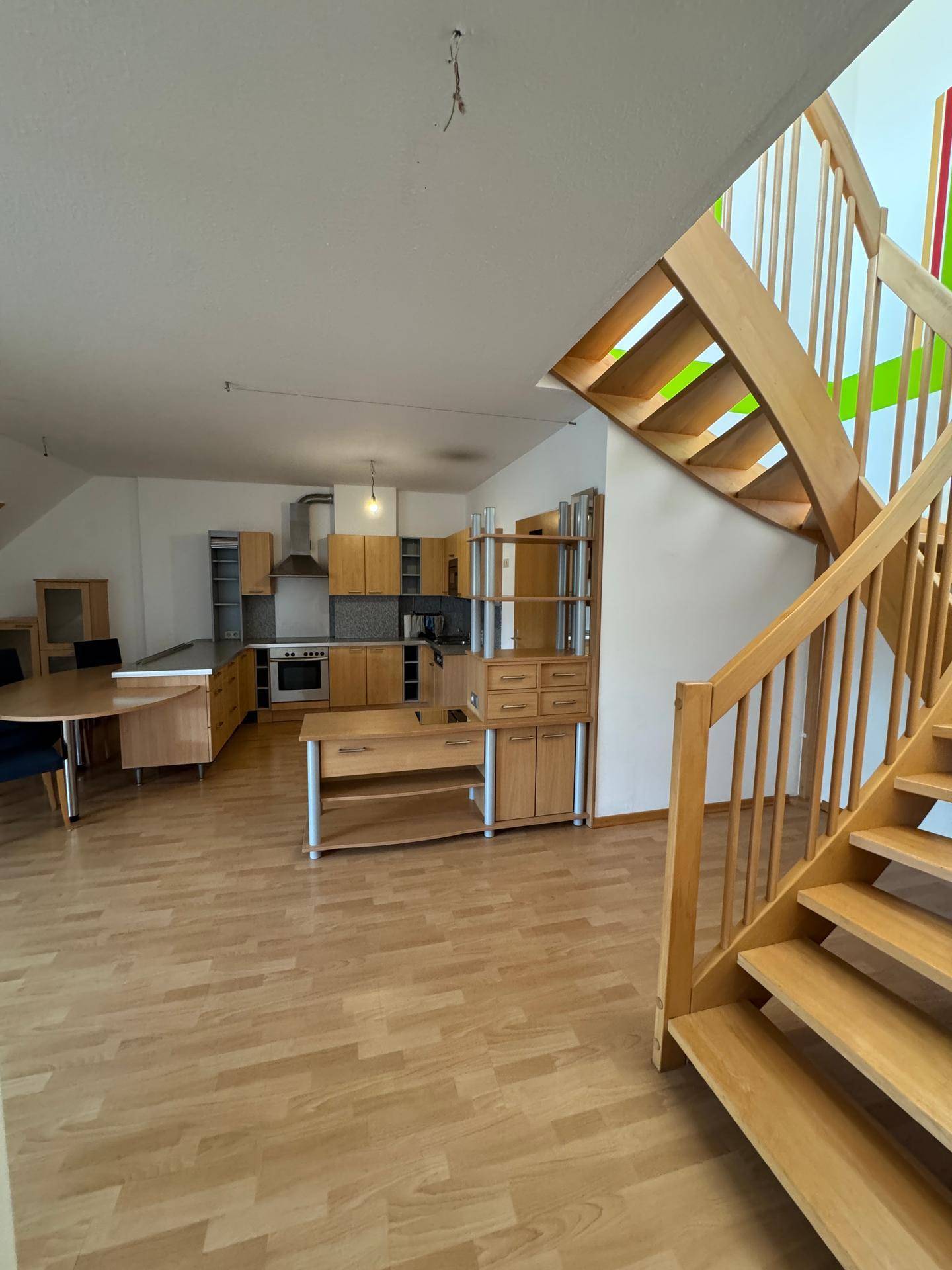 Offene Küche mit Essbereich, Holzmöbeln und einer Holztreppe, die in den oberen Stock führt.