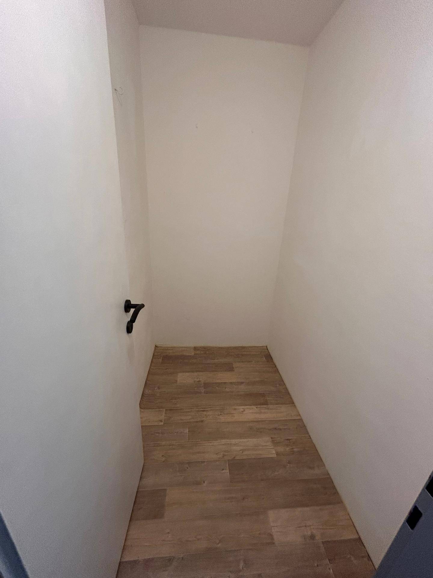 Kleiner, leerer Abstellraum mit Holzoptik-Boden, ideal für zusätzlichen Stauraum.