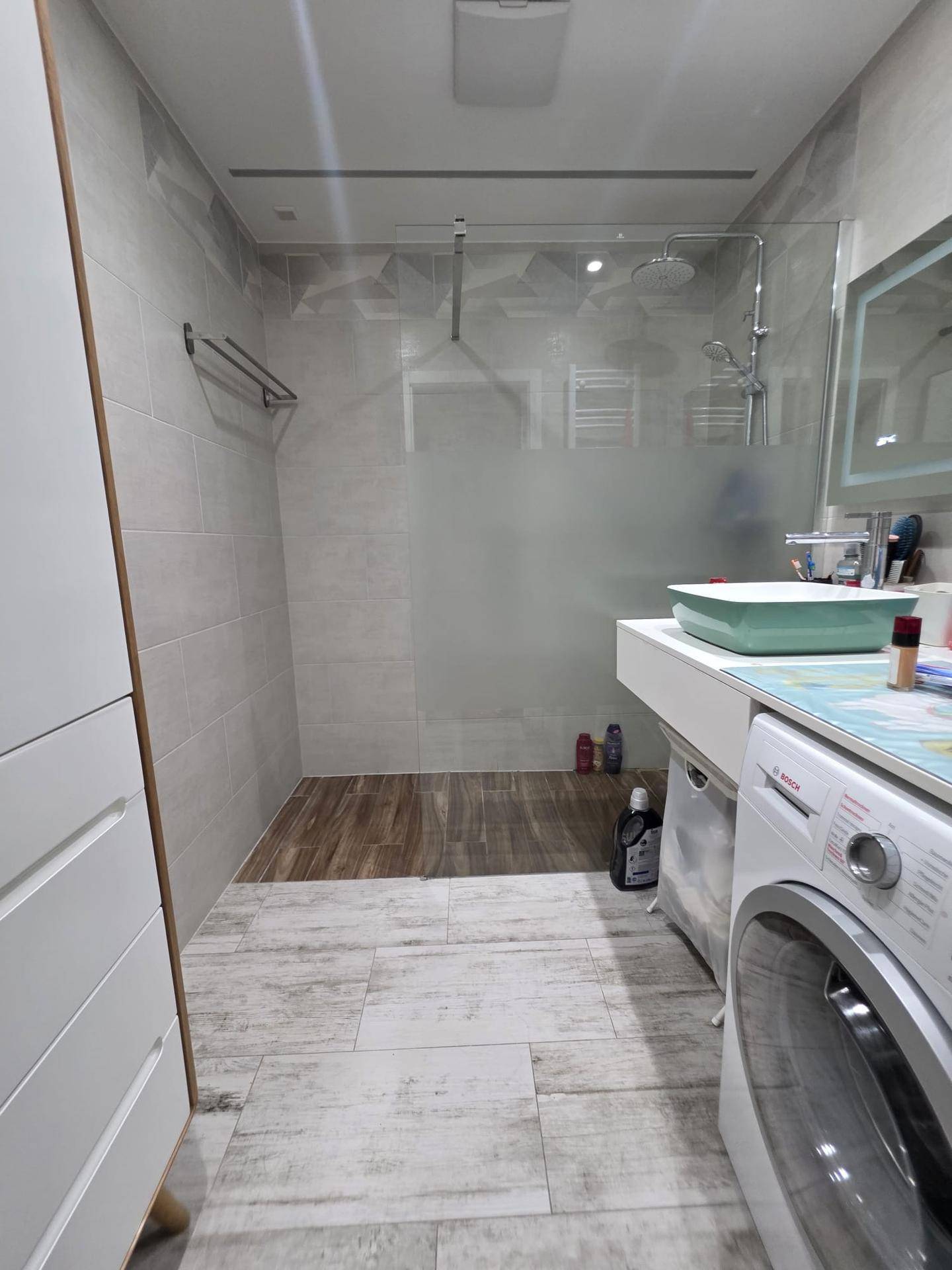 Modernes Badezimmer mit ebenerdiger Dusche, Waschmaschine und stilvollen Fliesen.