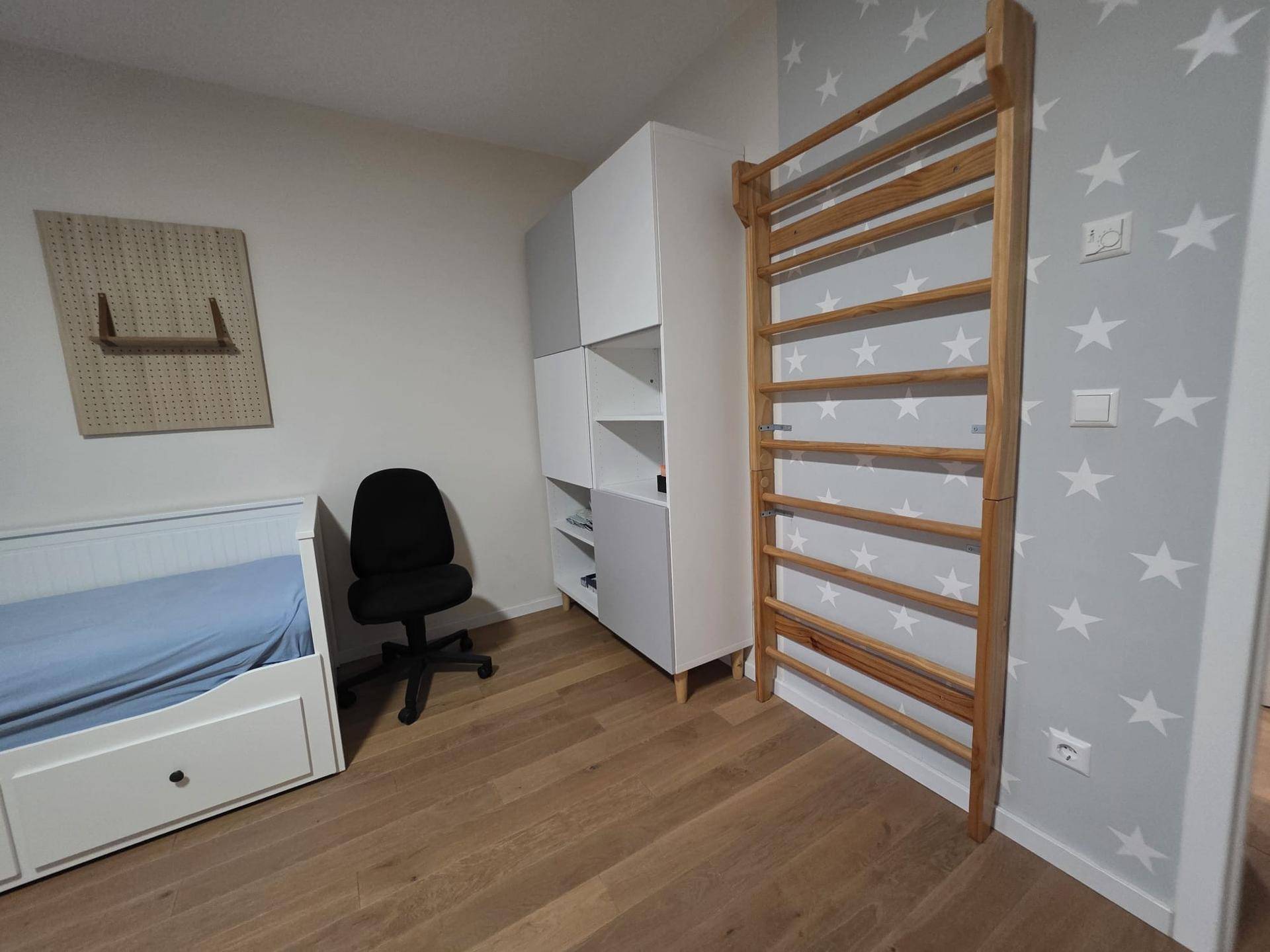 Kinderzimmer mit Sprossenwand, Sternen-Tapete, Bett und Schrank, ideal zum Spielen.