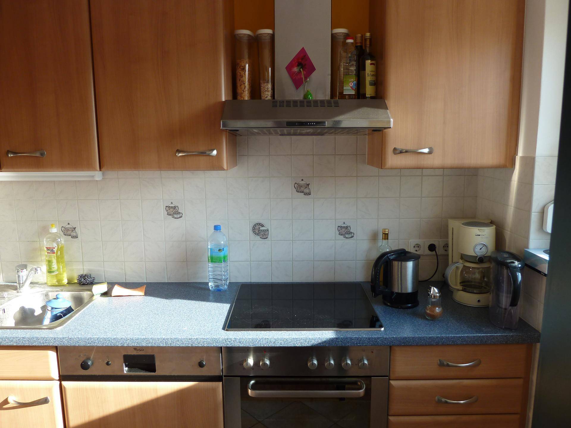 Funktionale Einbauküche mit Holzschränken, Induktionskochfeld, Backofen und Spülmaschine.