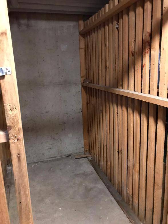 Einfacher Kellerraum mit robusten Holztrennwänden und Betonboden, ideal für Lagerzwecke und Abstellmöglichkeiten.