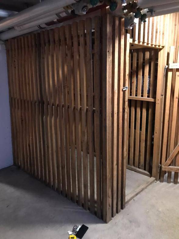 Geräumiger Kellerabteil mit Holztrennwänden und sichtbaren Deckenleitungen, bietet viel Stauraum.