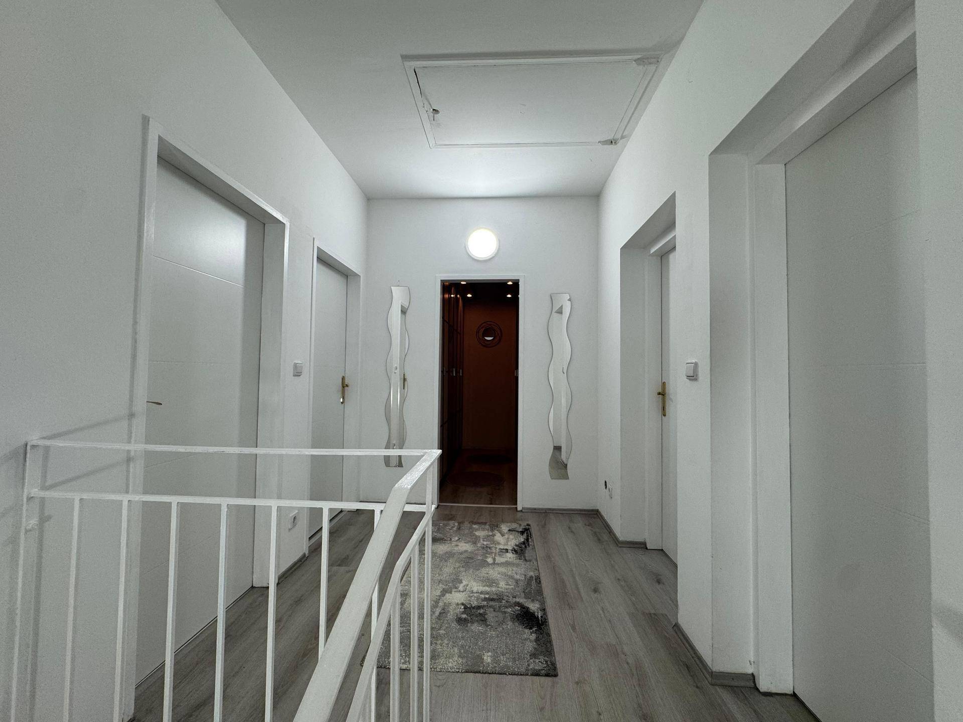 Heller Flur im Obergeschoss mit Laminatboden und Zugang zu mehreren Zimmern.