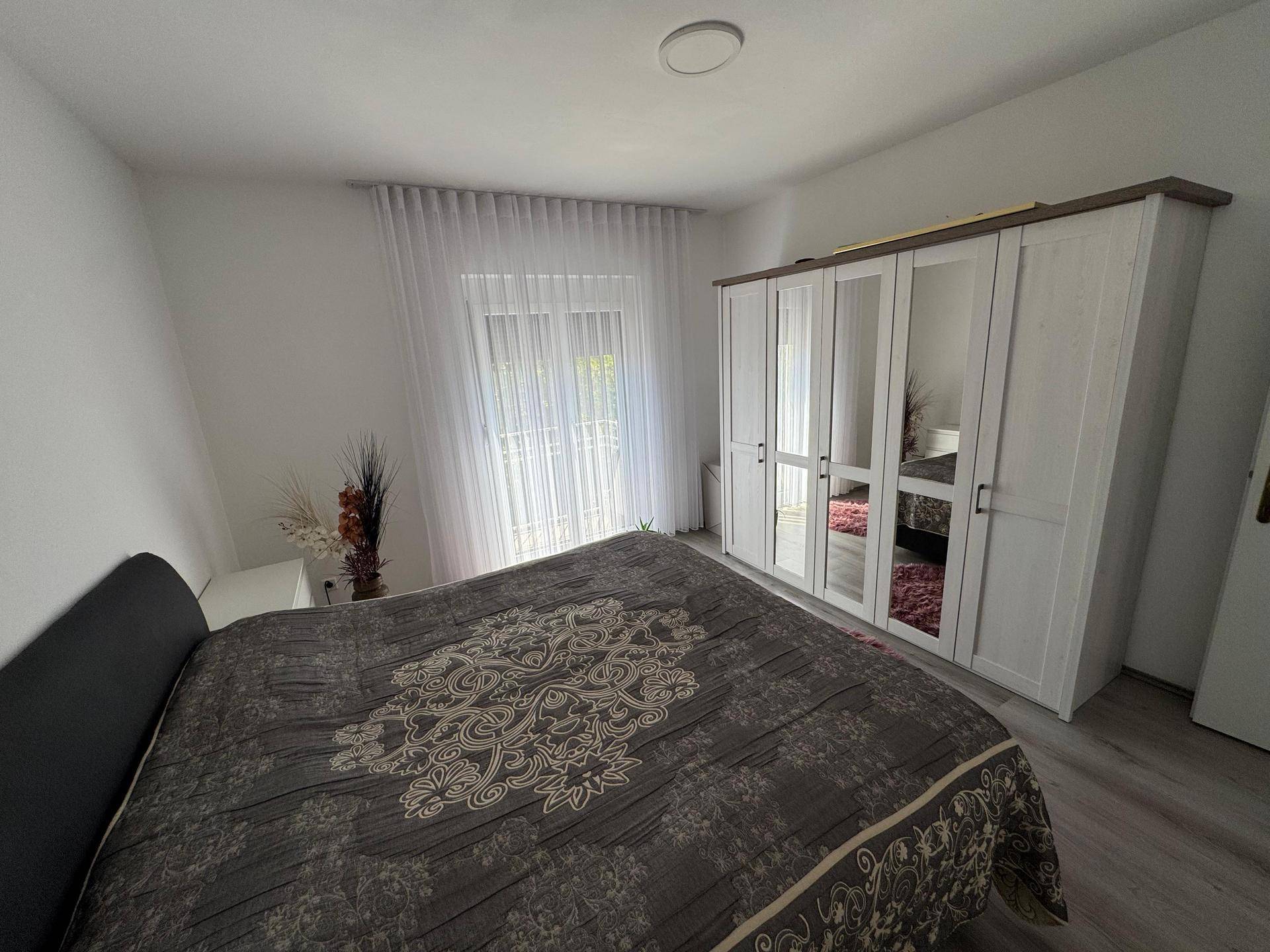 Geräumiges Schlafzimmer mit großem Kleiderschrank, Doppelbett und hellem Laminatboden.