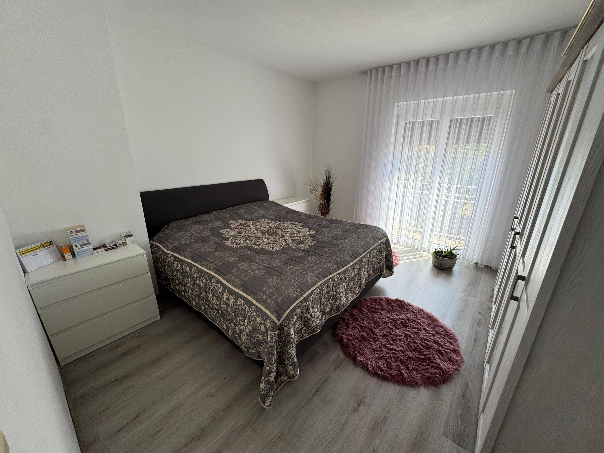 Schlafzimmer mit Doppelbett, Laminatboden und großem Kleiderschrank, gemütlich eingerichtet.
