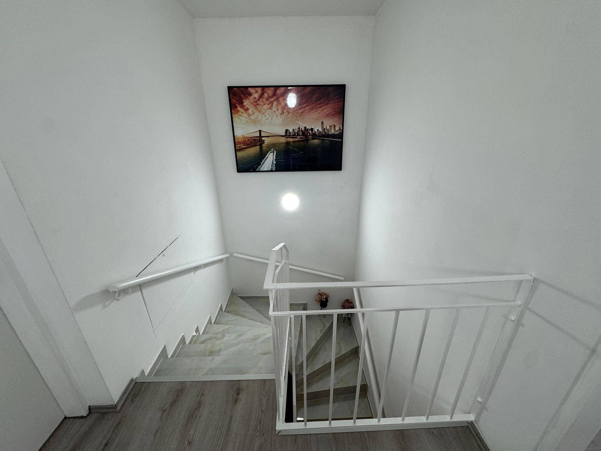 Treppenhaus mit modernem Kunstwerk und hellem Geländer, das die Stockwerke verbindet.