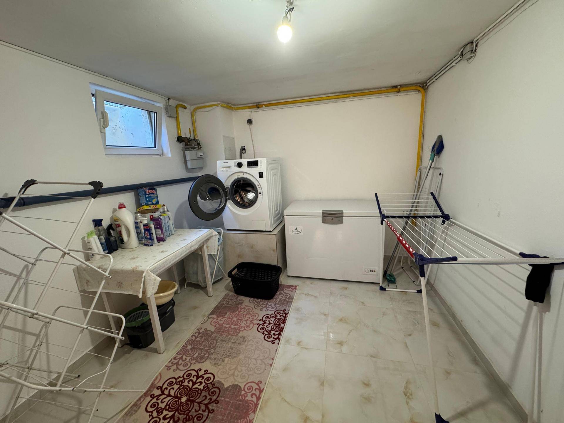 Hauswirtschaftsraum im Keller mit Waschmaschine, Gefriertruhe und Wäscheständer, ideal für den Haushalt.
