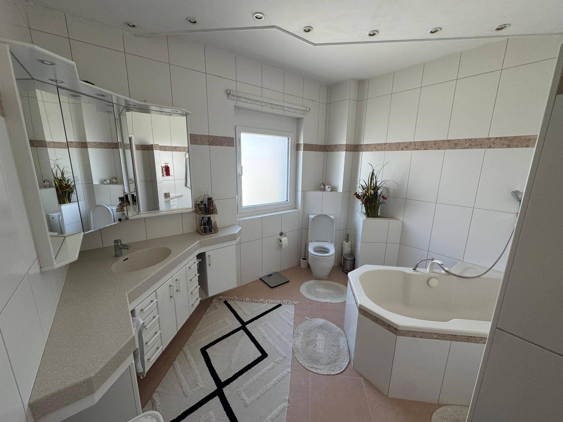 Geräumiges Badezimmer mit Doppelwaschbecken, Spiegelschrank, Toilette und Eckbadewanne.