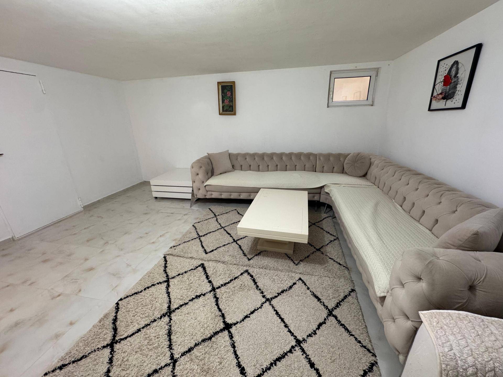 Geräumiges Wohnzimmer mit großem Ecksofa, Couchtisch und modernem Teppich auf hellem Fliesenboden.