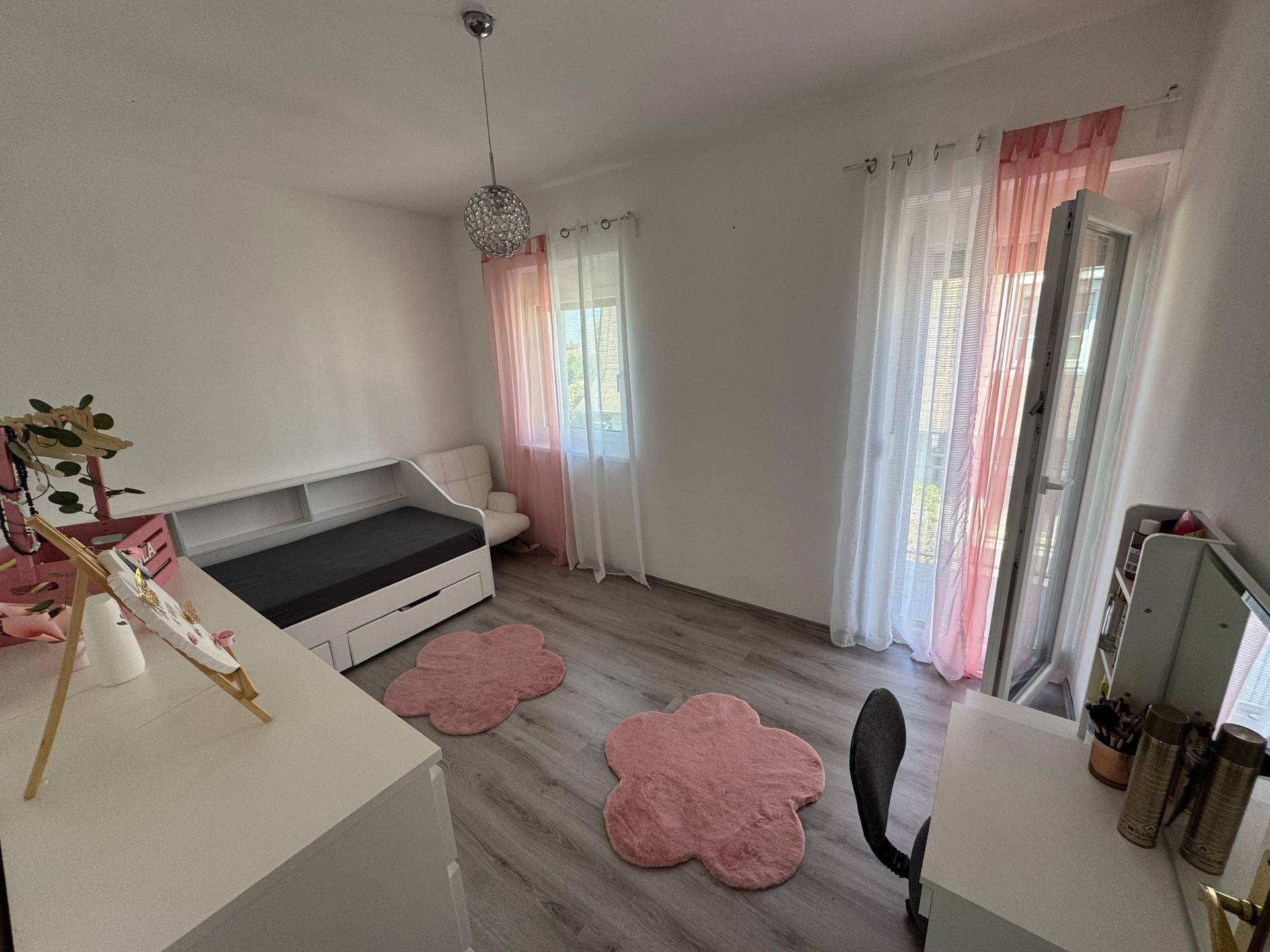 Kinderzimmer mit Tagesbett, Schreibtisch und rosa Dekoration, hell und freundlich gestaltet.