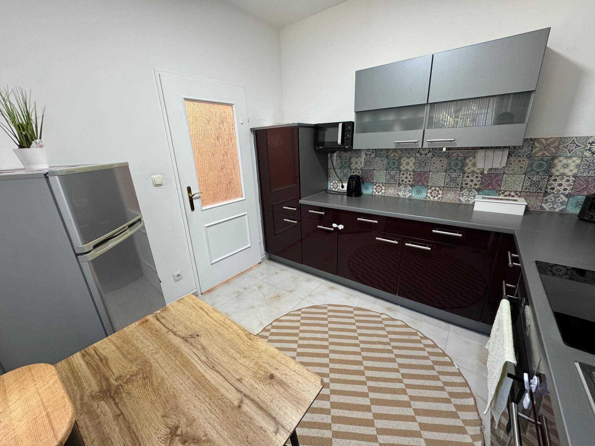 Funktionale Küche mit Kühlschrank, Mikrowelle und Essbereich, ideal für den täglichen Gebrauch.