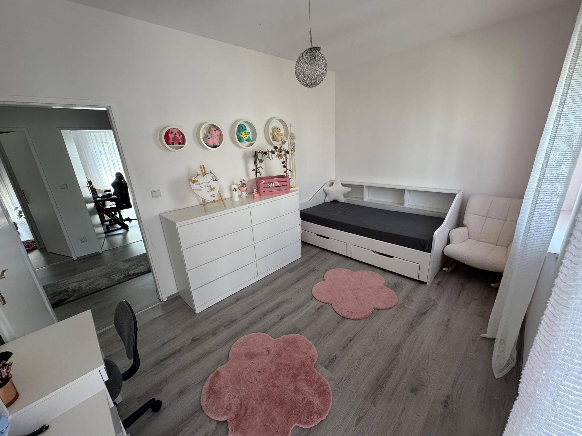 Helles Kinderzimmer mit modernem Bett, Kommode und Schreibtisch, ideal für junge Bewohner.