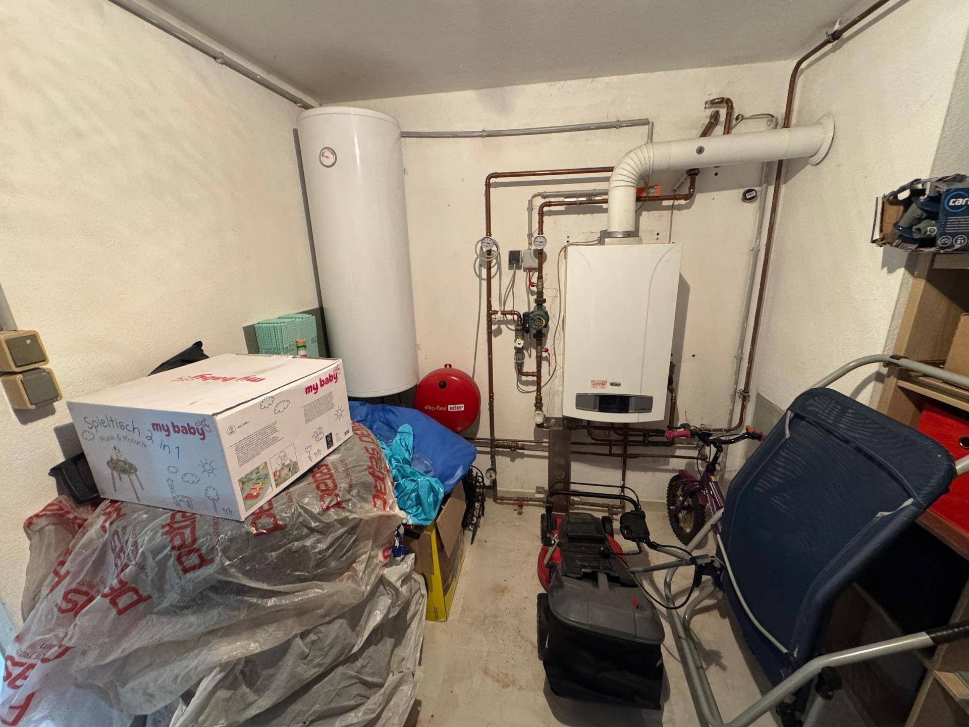 Technikraum im Keller mit Warmwasserbereiter und Heizungsanlage, bietet zusätzlichen Stauraum.