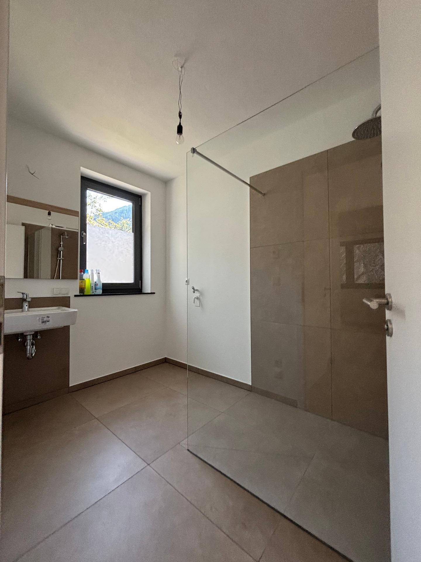 Modernes Badezimmer mit großer begehbarer Dusche, Fenster und Einzelwaschbecken.