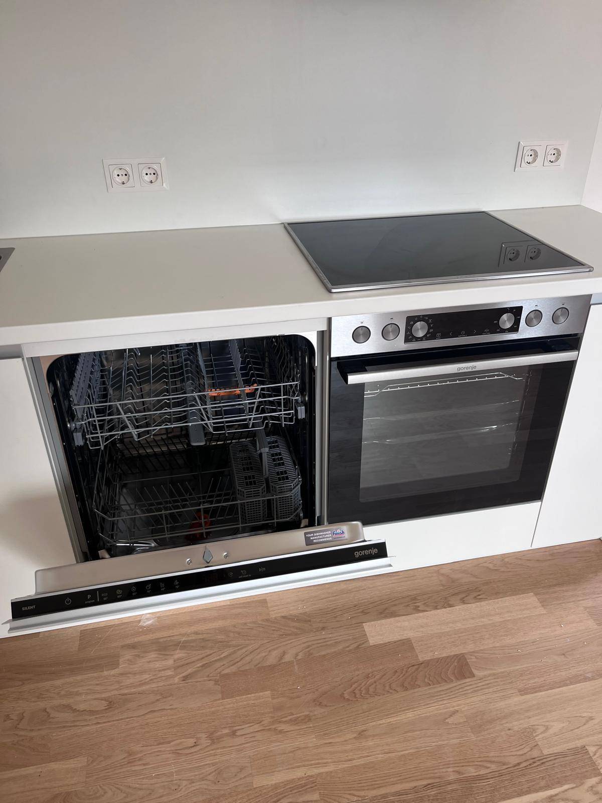 Detailansicht der modernen Küche mit integriertem Geschirrspüler, Backofen und Induktionskochfeld.