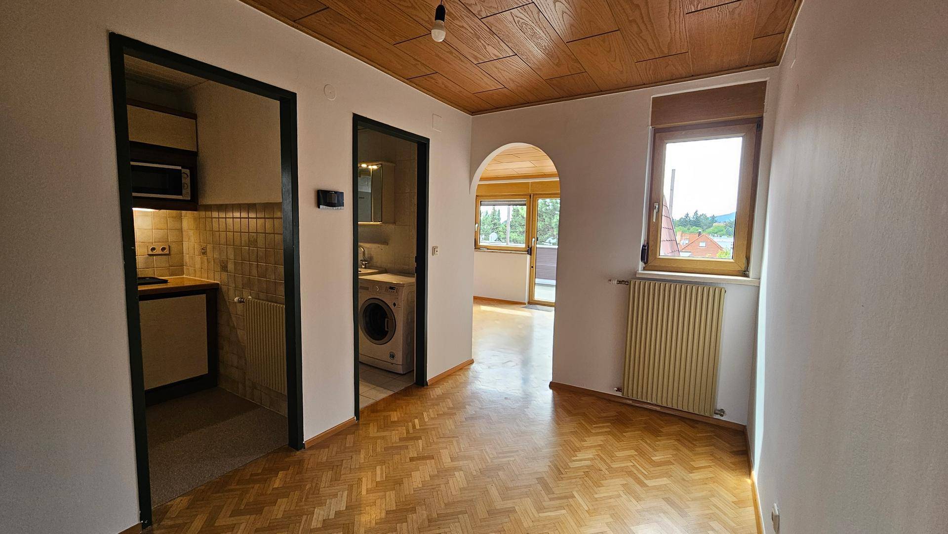 Flur mit Fischgrätparkett, Holzdecke und Zugang zu verschiedenen Räumen.