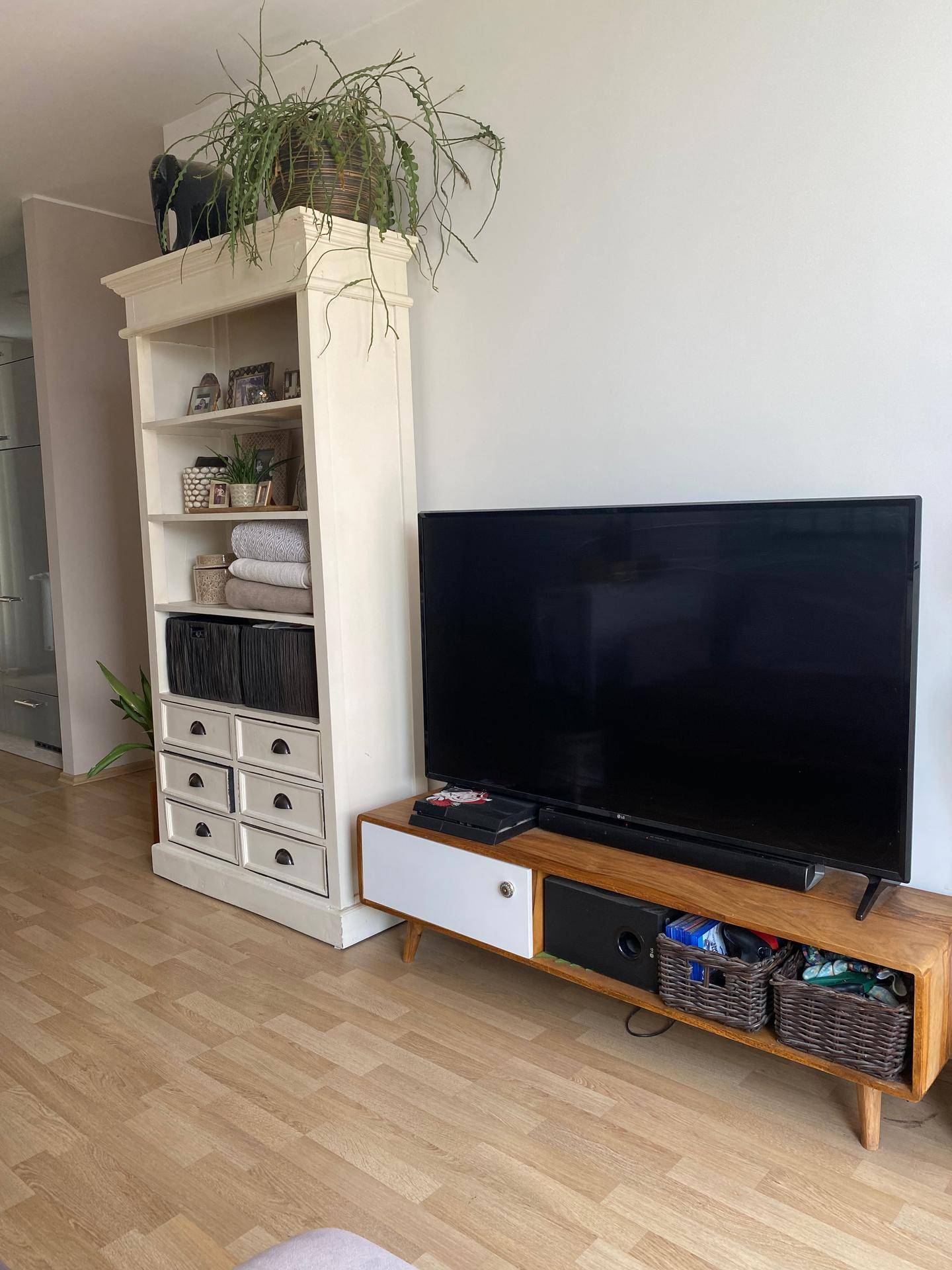 Wohnbereich mit Fernseher auf einem Medienmöbel und einem hohen weißen Bücherregal.