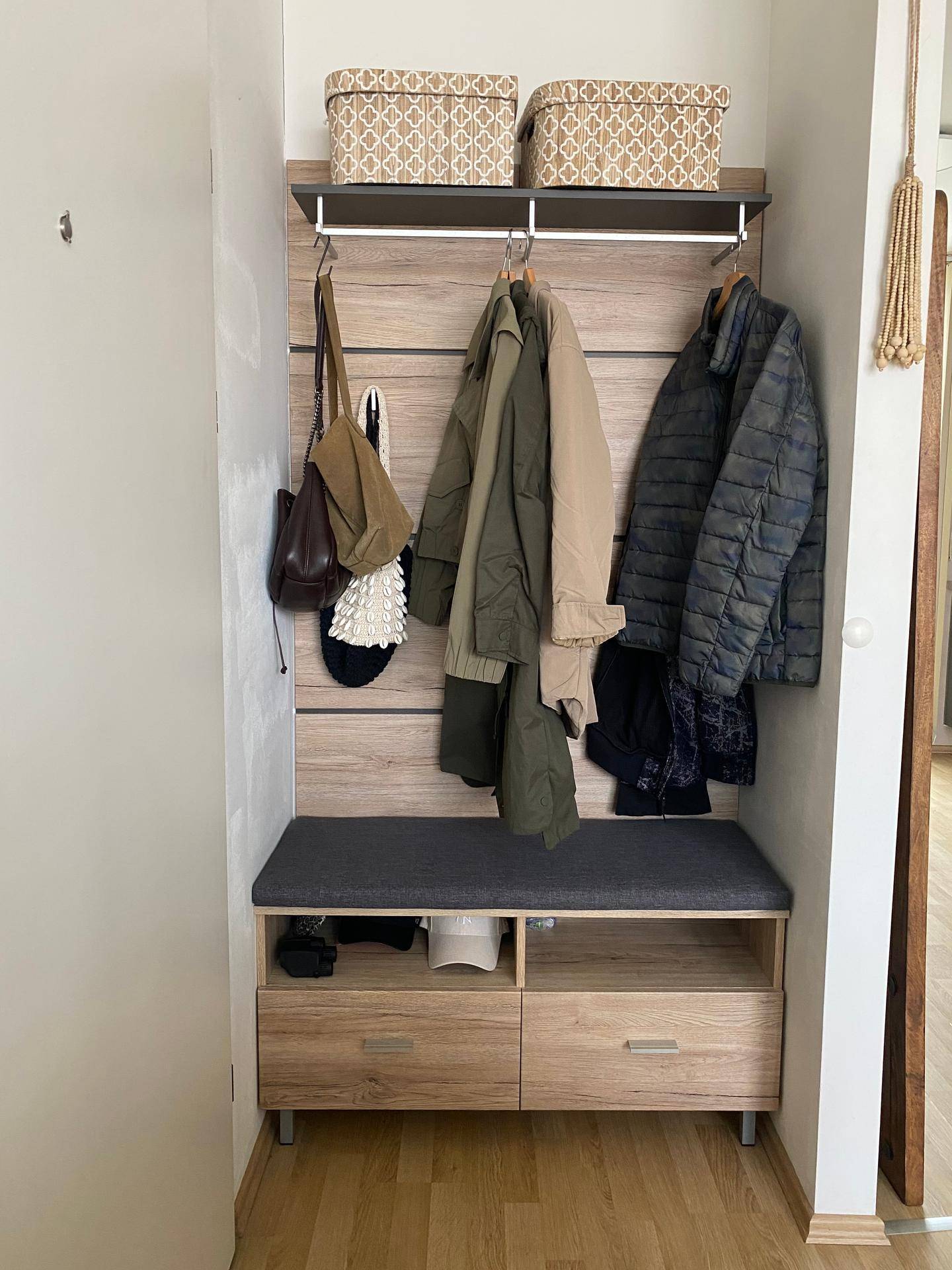 Garderobenbereich mit Holzpaneel, Sitzbank und Stauraum für Kleidung und Accessoires.