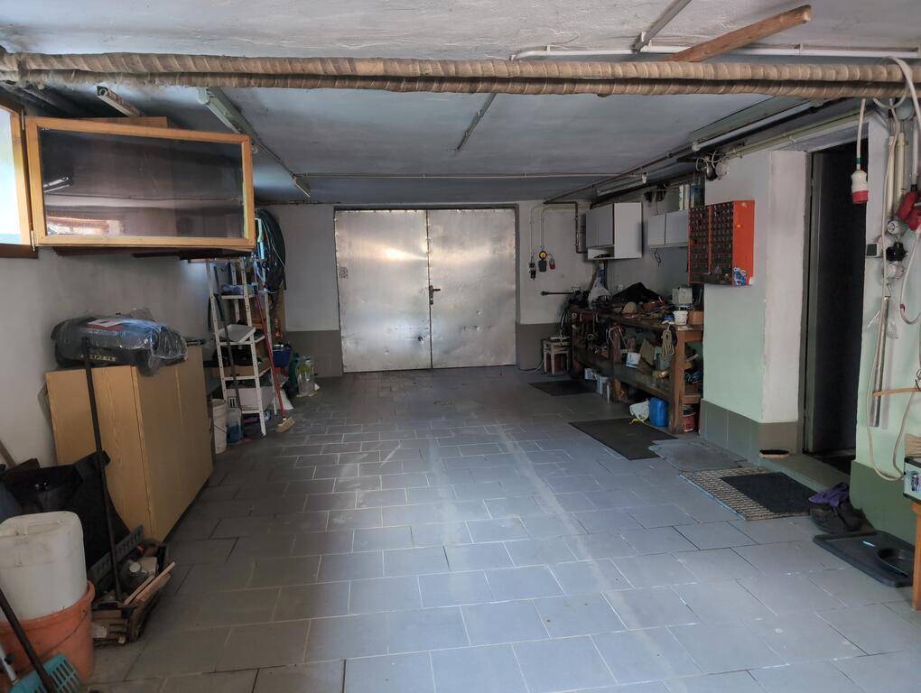 Geräumige Garage mit Fliesenboden, Werkbank und Stauraum, ideal für Hobby und Lagerung.