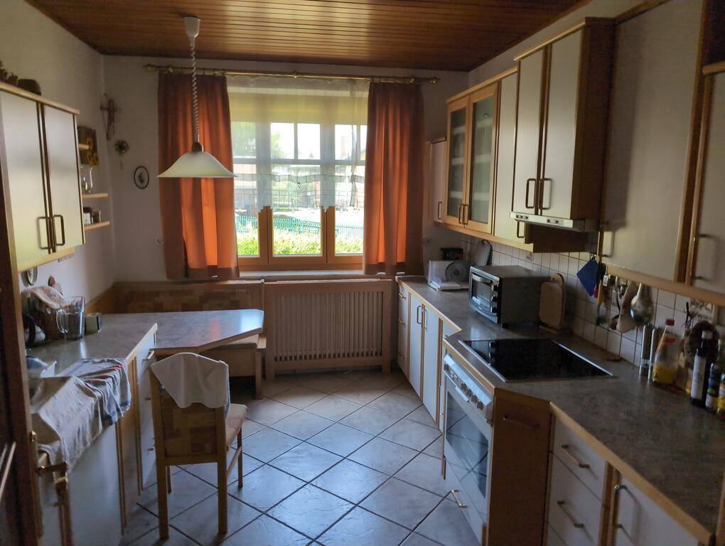 Gemütliche Küche mit Einbaumöbeln, Essbereich am Fenster und Fliesenboden, ideal für Familienmahlzeiten.