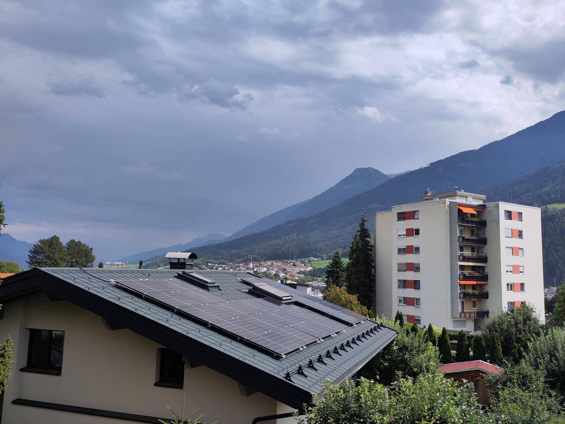 Dach eines Gebäudes mit Photovoltaikanlage und Bergblick im Hintergrund.