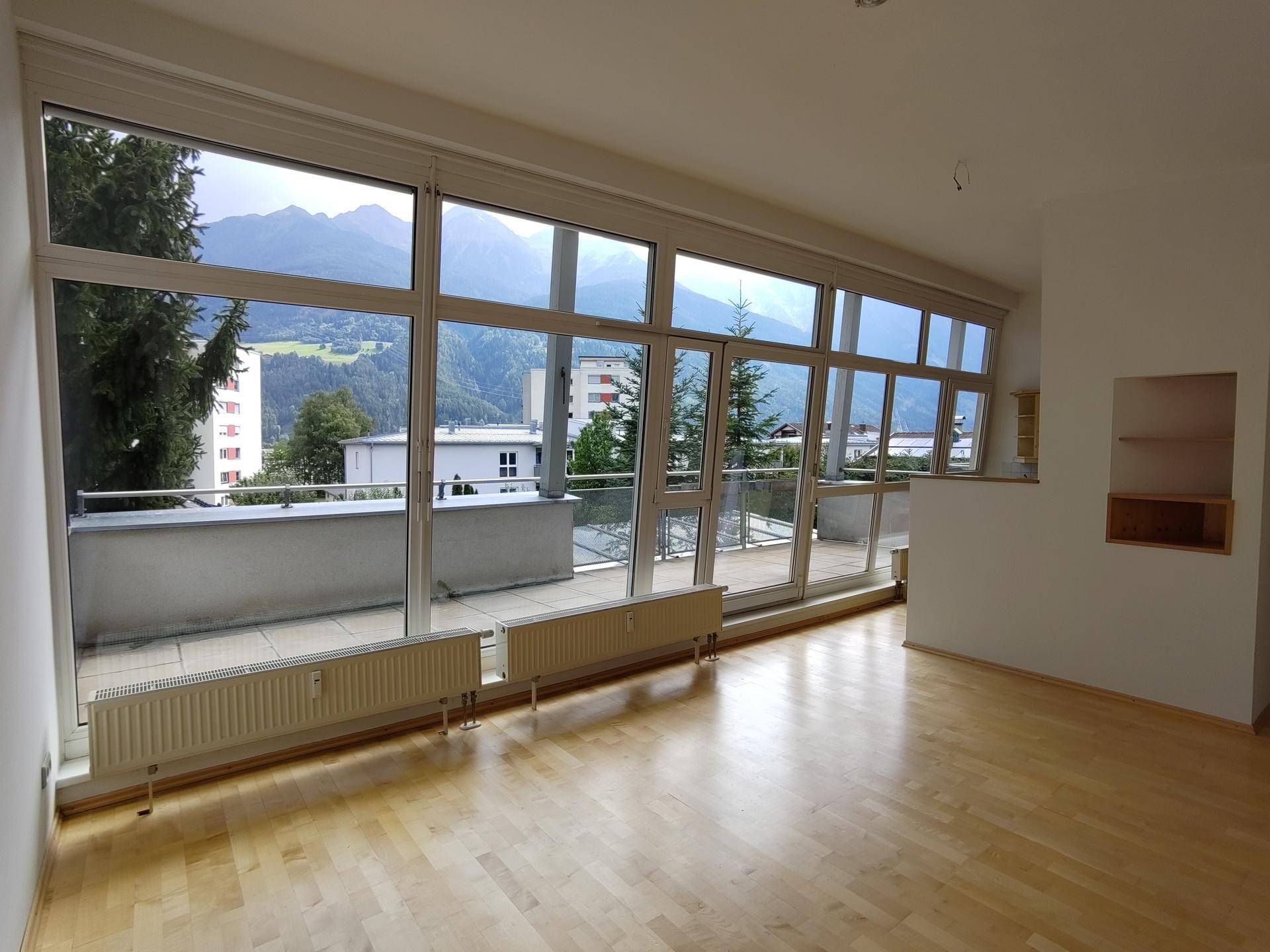 Lichtdurchflutetes Wohnzimmer mit großen Fenstern und Bergblick.