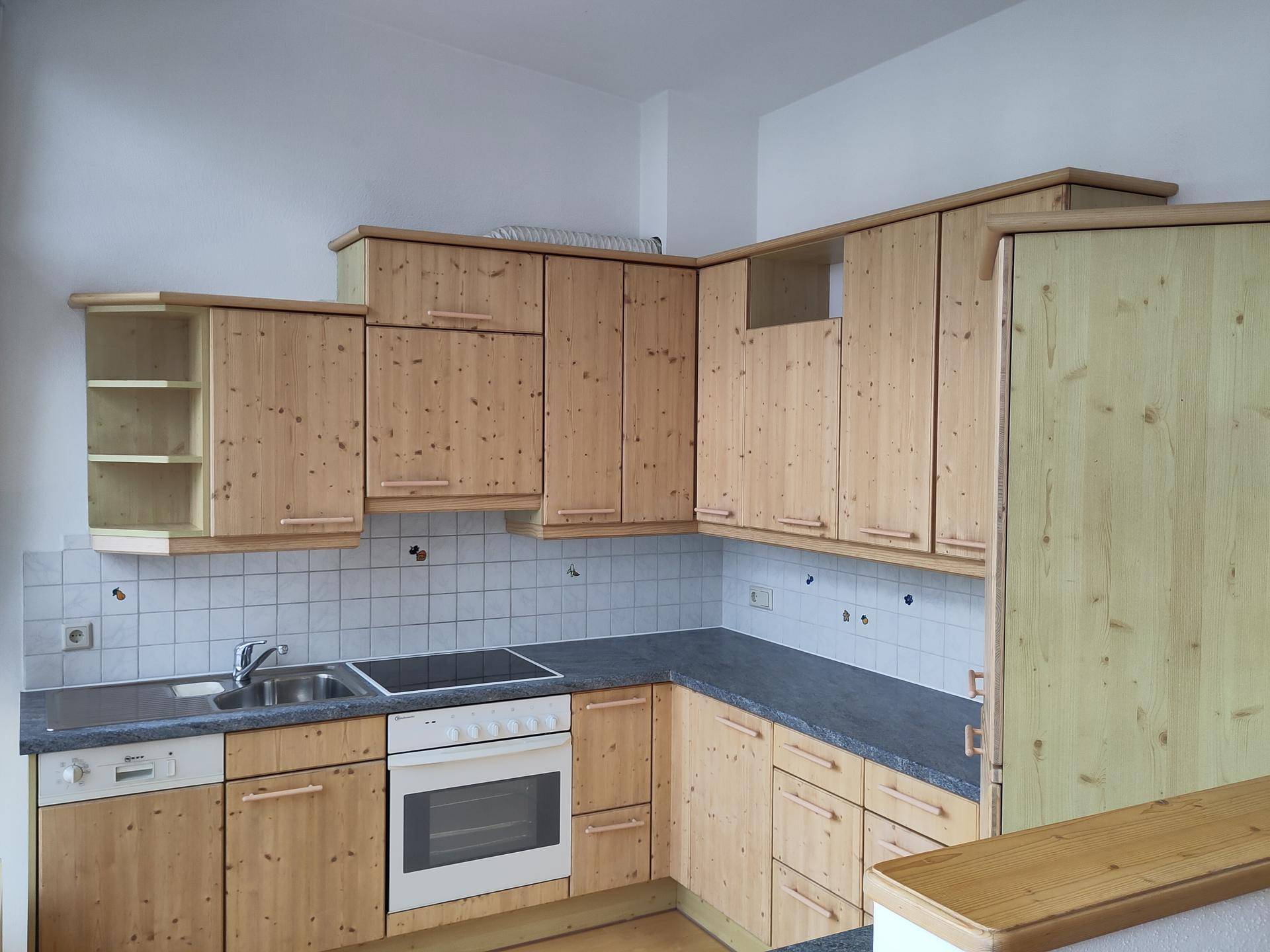Funktionale Küche mit hellen Holzschränken, integriertem Herd und Fliesenrückwand.