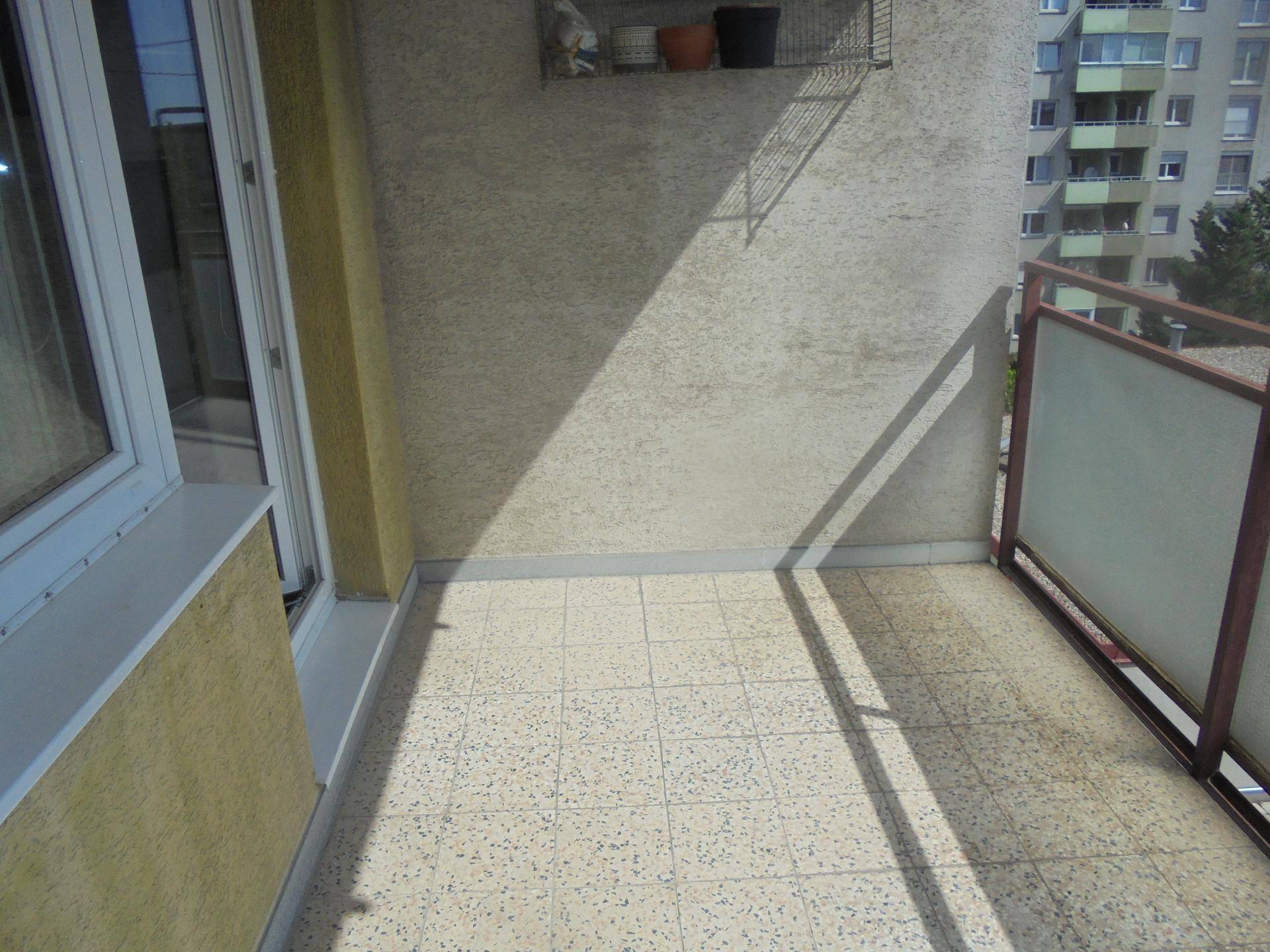Kleiner Balkon mit Fliesenboden und Blick auf umliegende Gebäude.