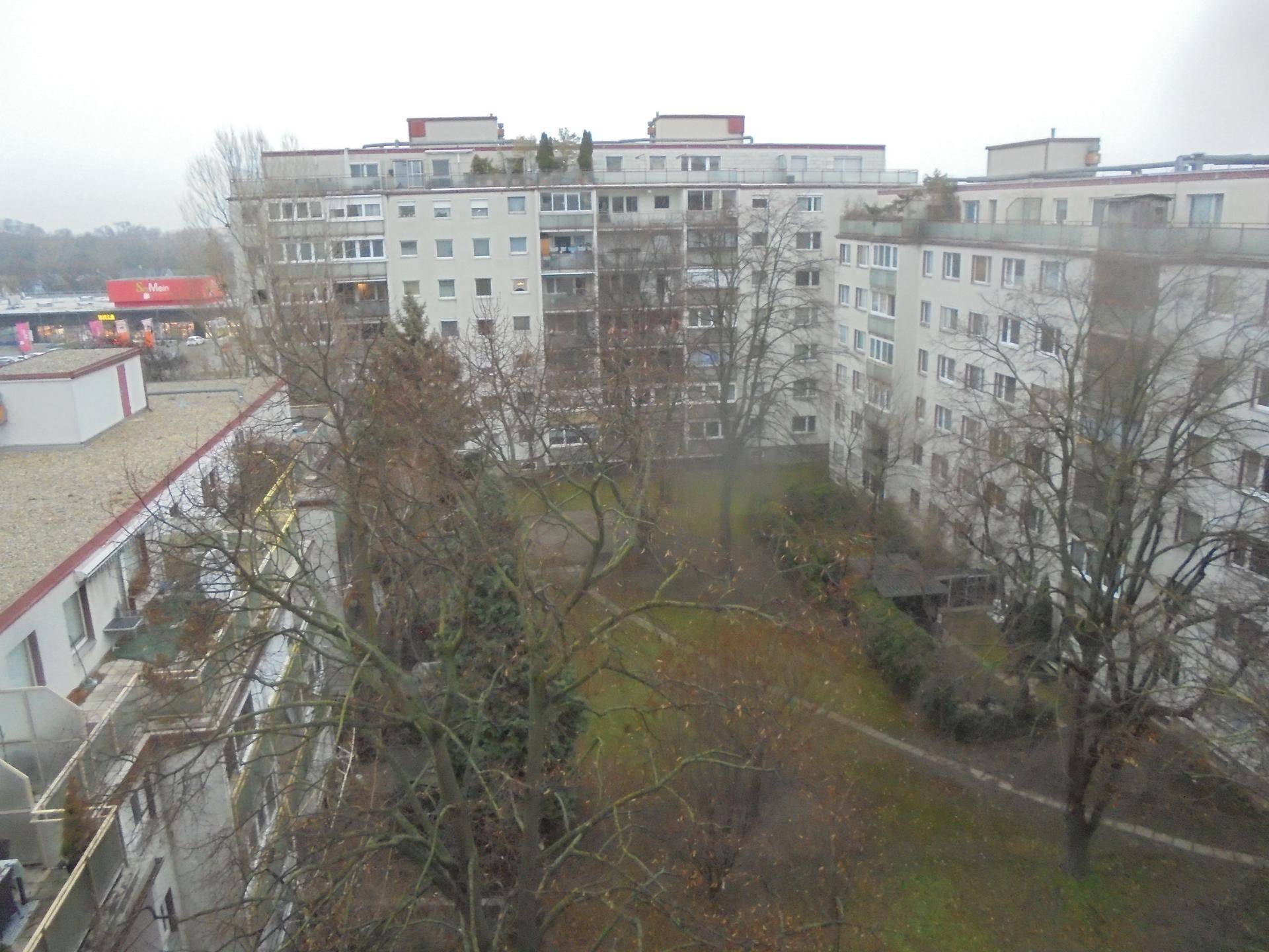 Blick von oben auf einen begrünten Innenhof umgeben von Wohngebäuden.