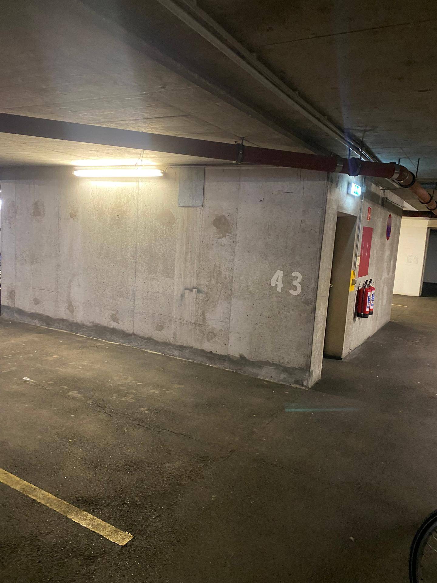 Blick in eine Tiefgarage mit Betonwänden, Nummer 43 an der Wand und einem Feuerlöscher.