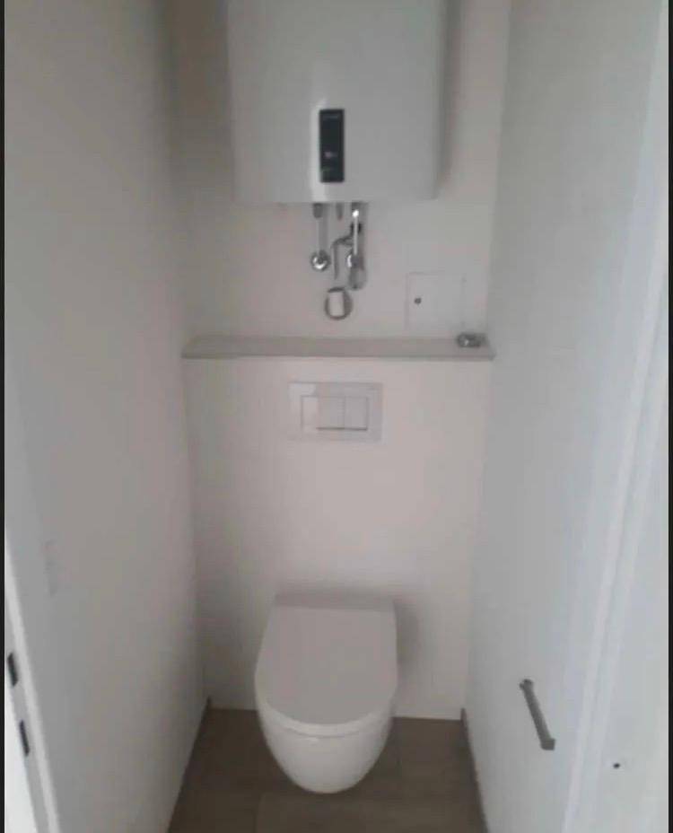 Kleines, helles Gäste-WC mit wandhängender Toilette und einem Warmwasserboiler.
