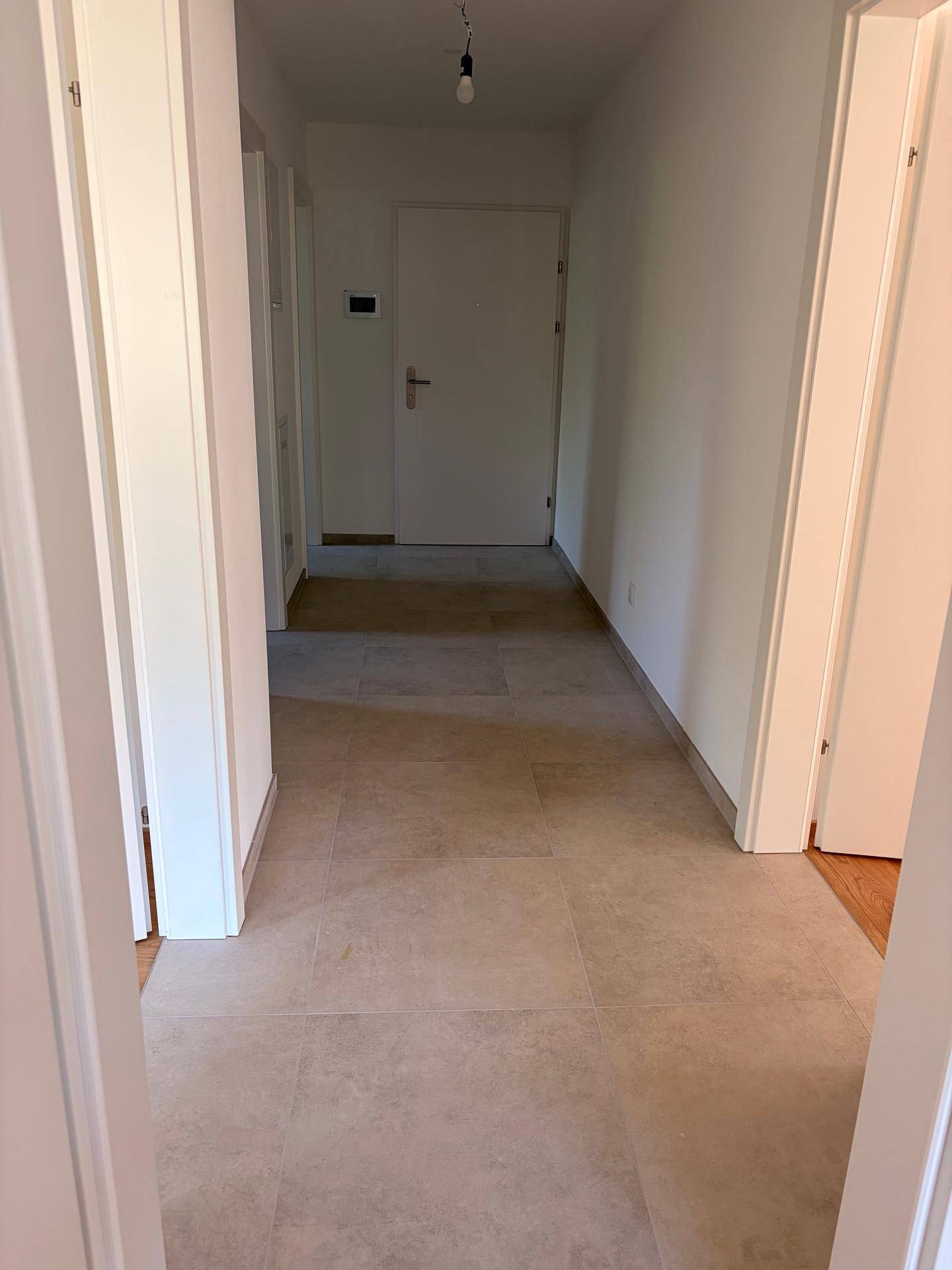 Heller Flur mit Fliesenboden und Zugang zu verschiedenen Zimmern der Wohnung.