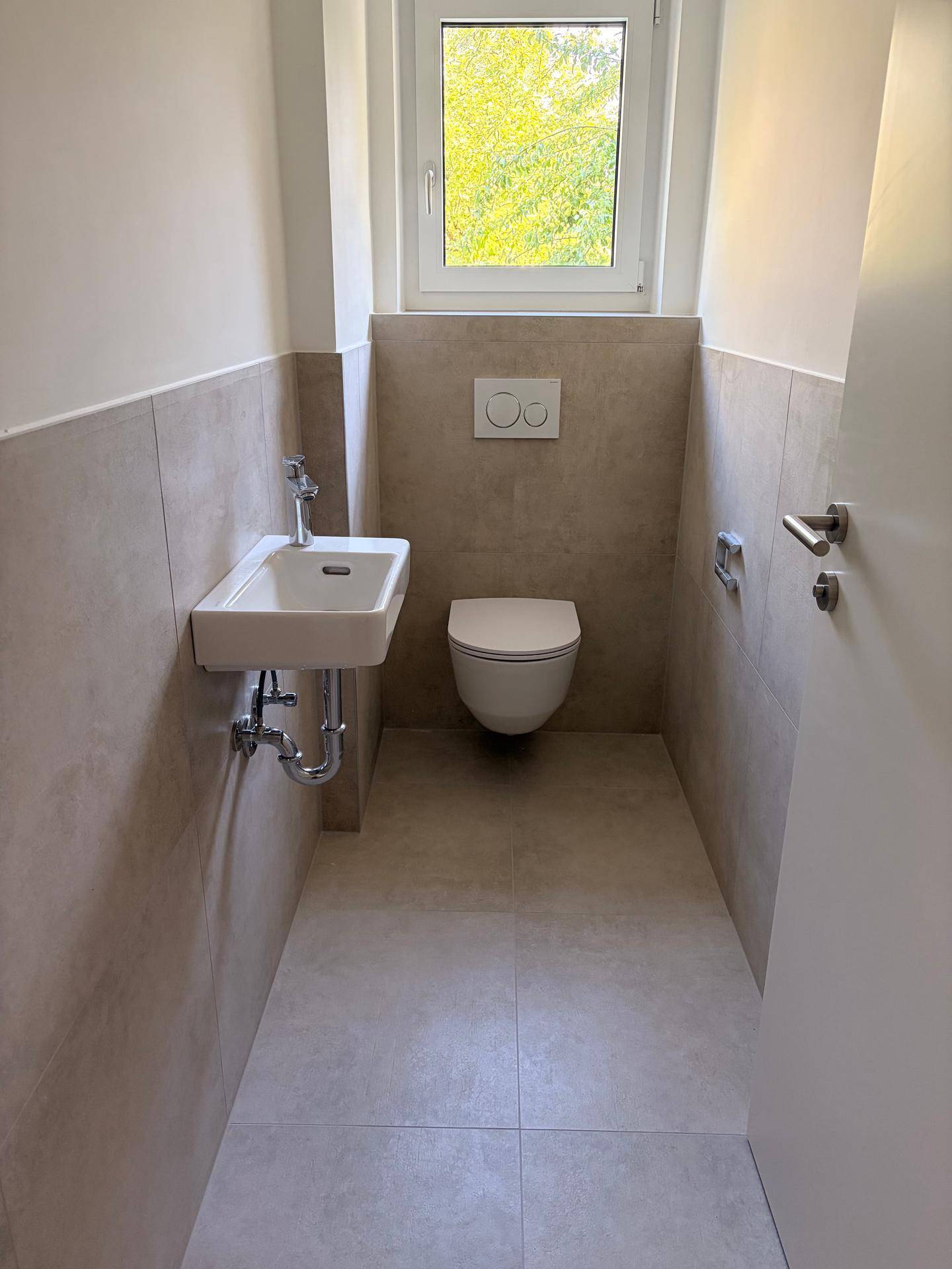 Modernes Gäste-WC mit Wand-WC, kleinem Waschbecken und Fenster.
