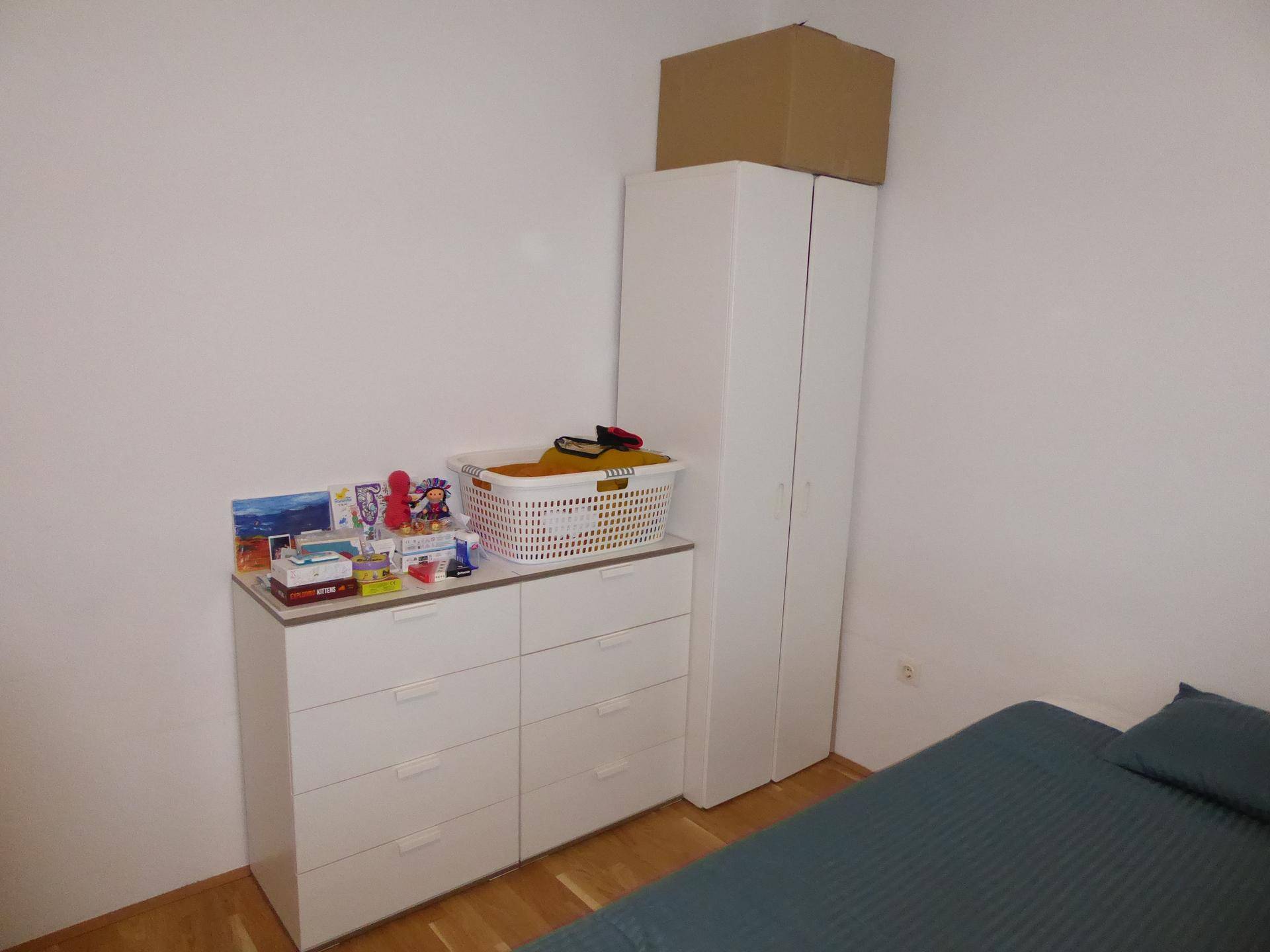 Schlafzimmerecke mit weißer Kommode und Kleiderschrank, bietet Stauraum.