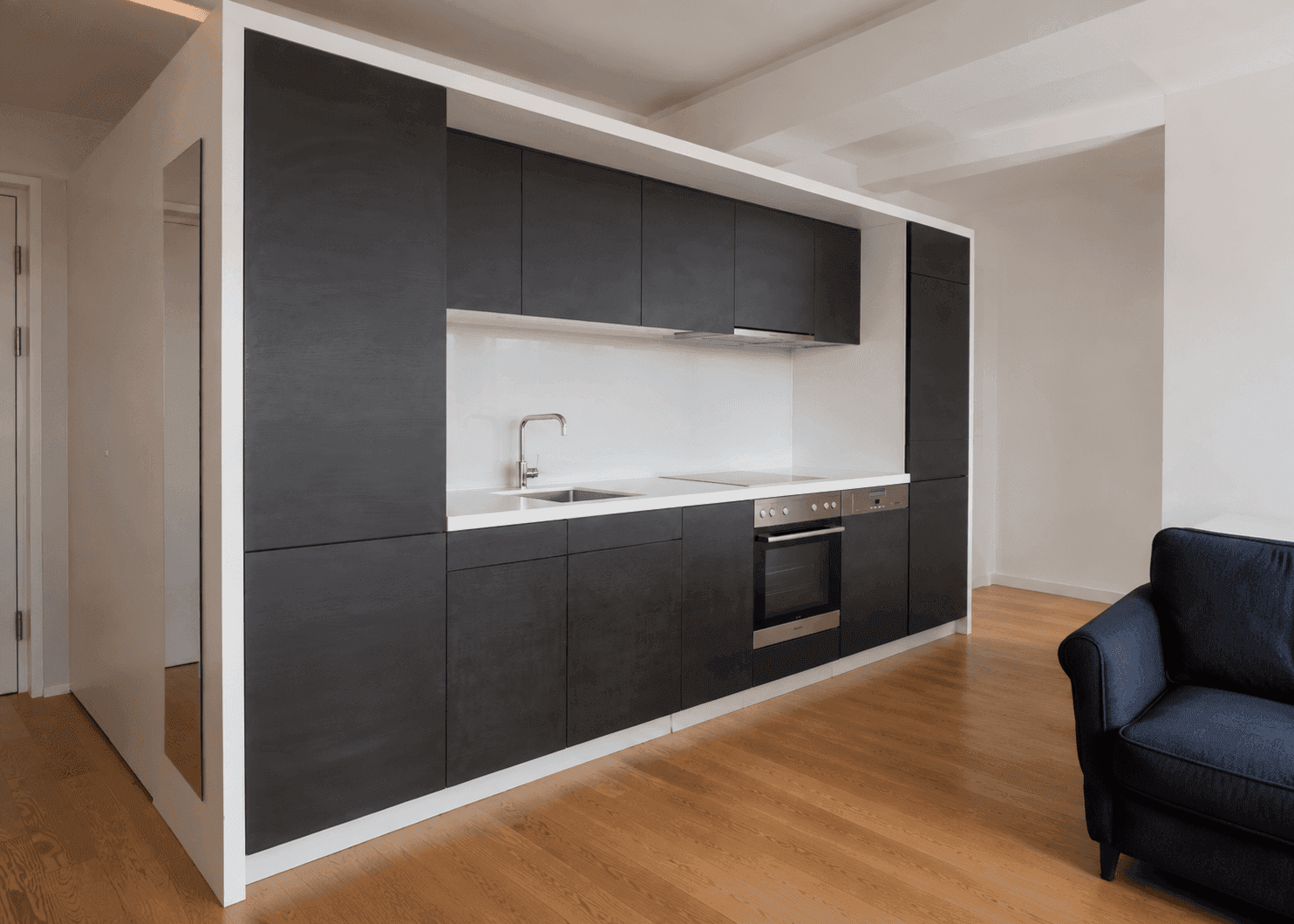 Elegante schwarze Einbauküche mit minimalistischem Design und Holzboden in einem offenen Raum.