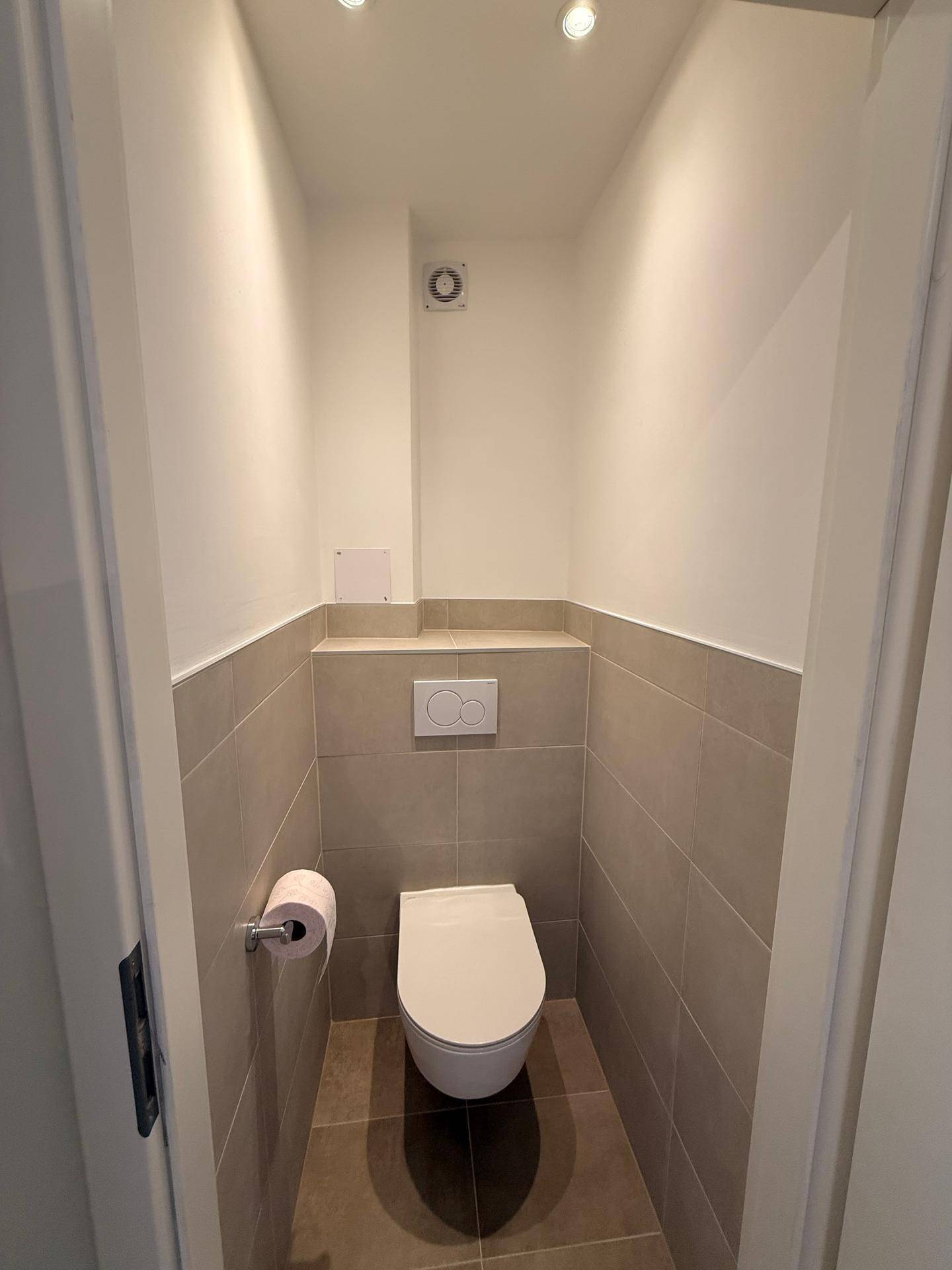 Modernes Gäste-WC mit Wand-WC, Fliesen und integrierter Spülung.