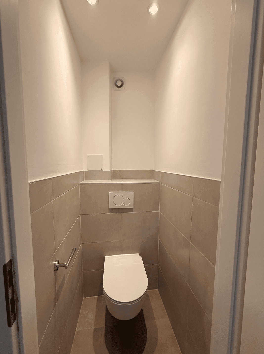 Kleines, separates WC mit Wand-WC und Fliesen in neutralen Beigetönen.