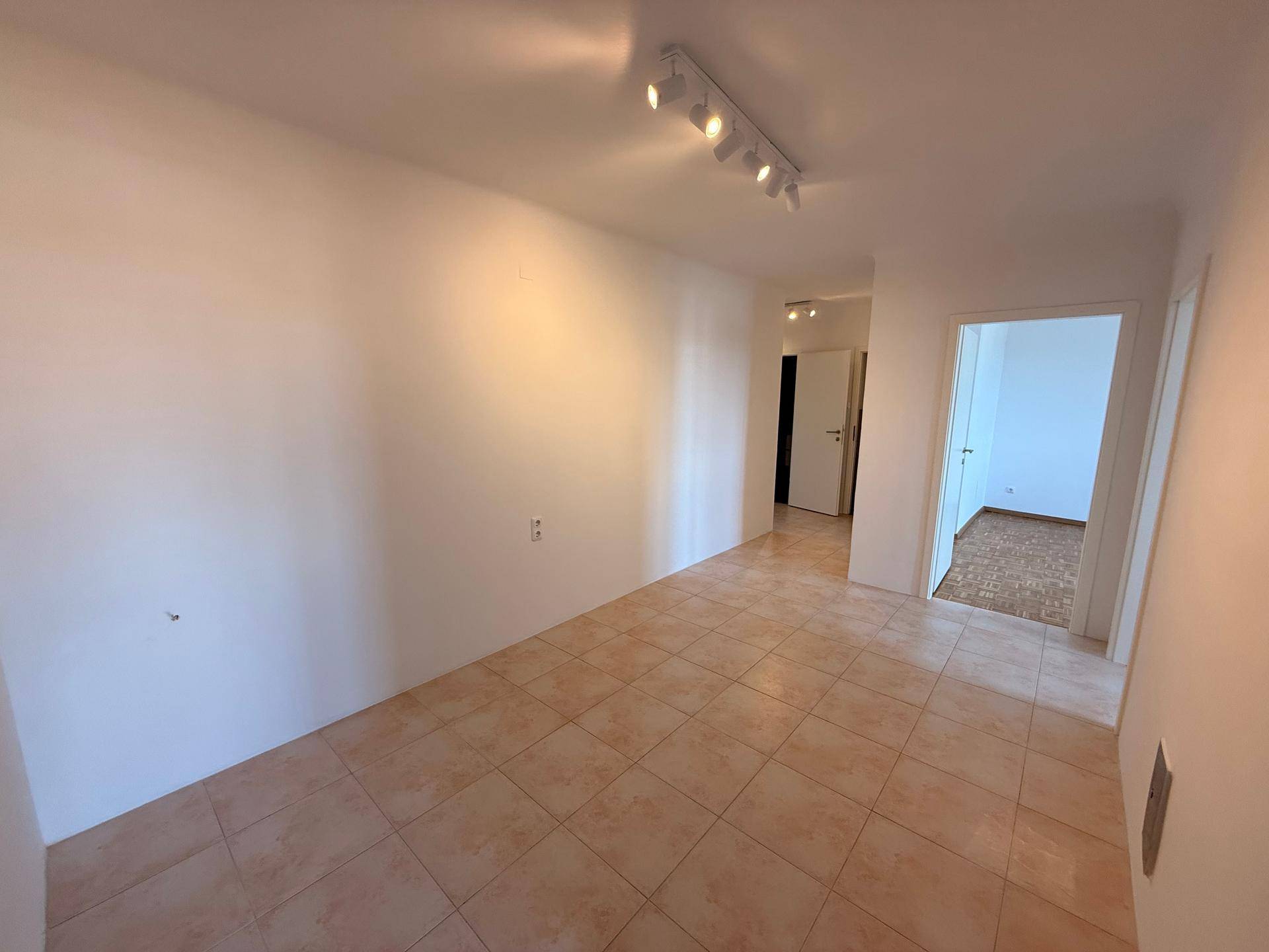Heller Flur mit Fliesenboden, der zu weiteren Räumen der Wohnung führt.