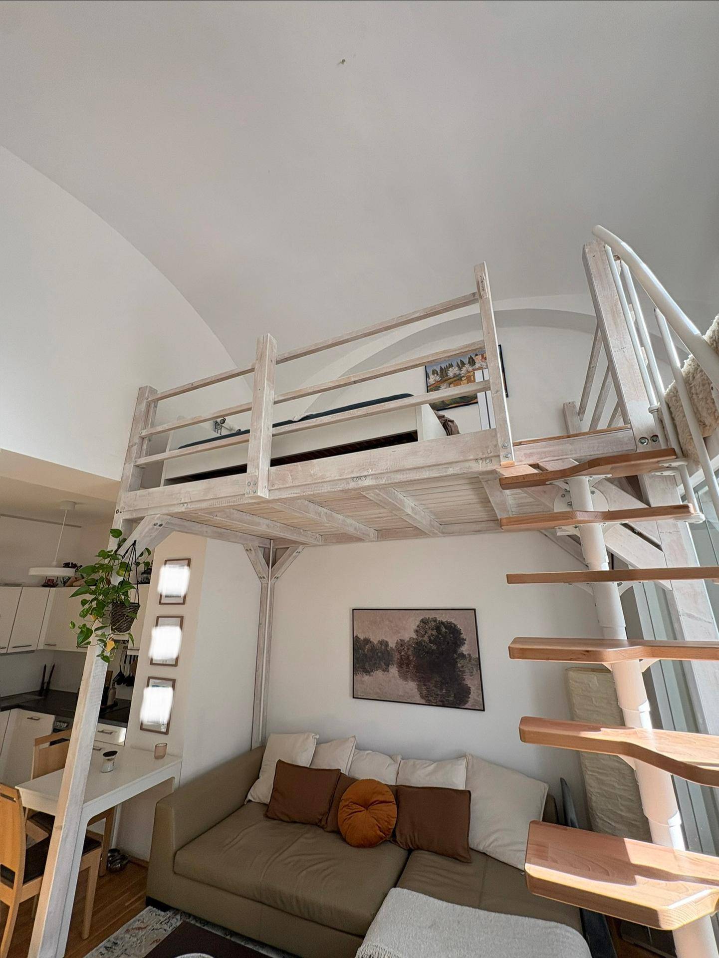 Blick auf die Holz-Loftstruktur und die Wendeltreppe im hellen Wohnbereich mit Sofa.
