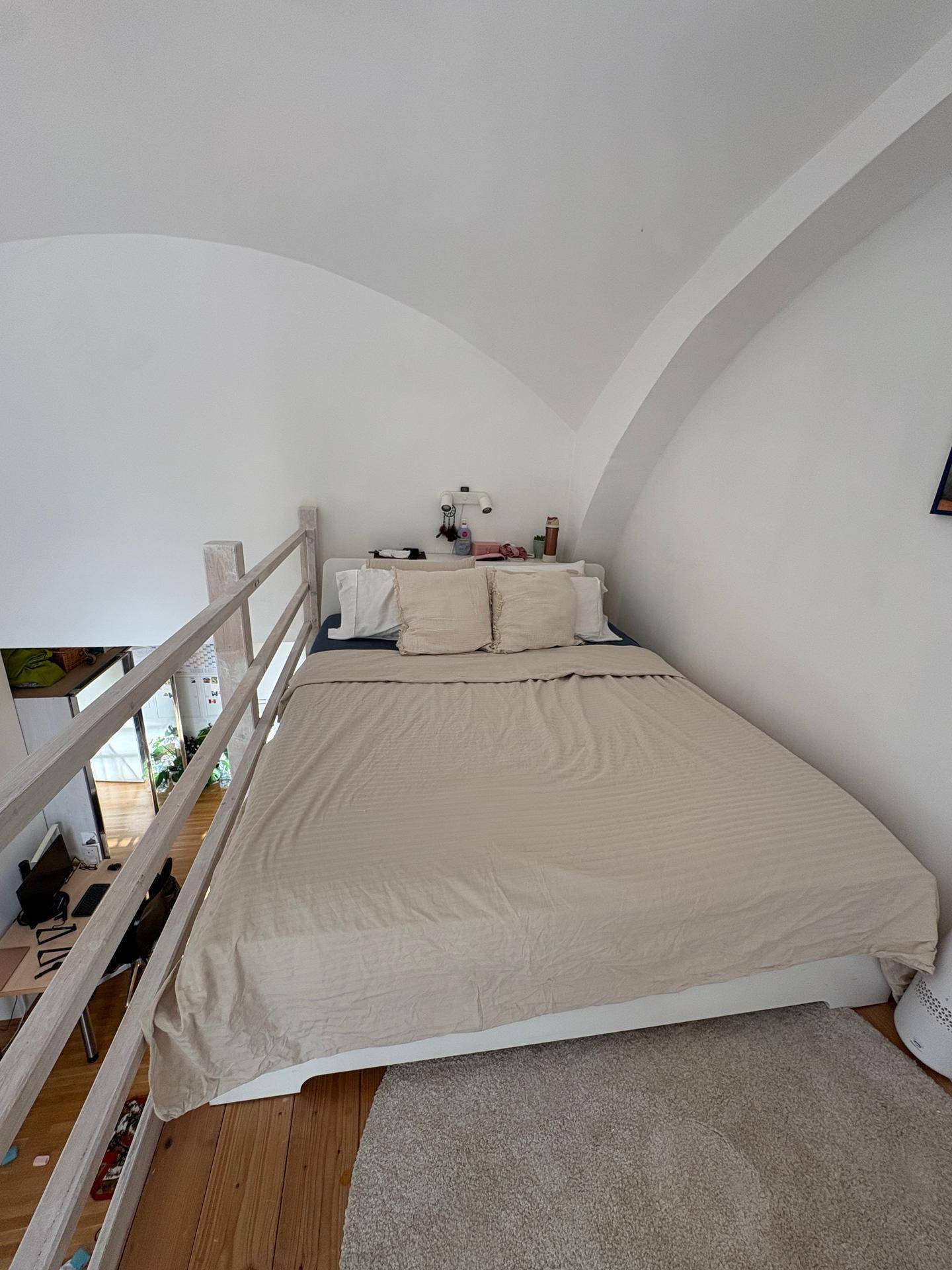 Gemütliches Schlafzimmer im Loftbereich mit Bett und Teppich, unter einer Gewölbedecke.