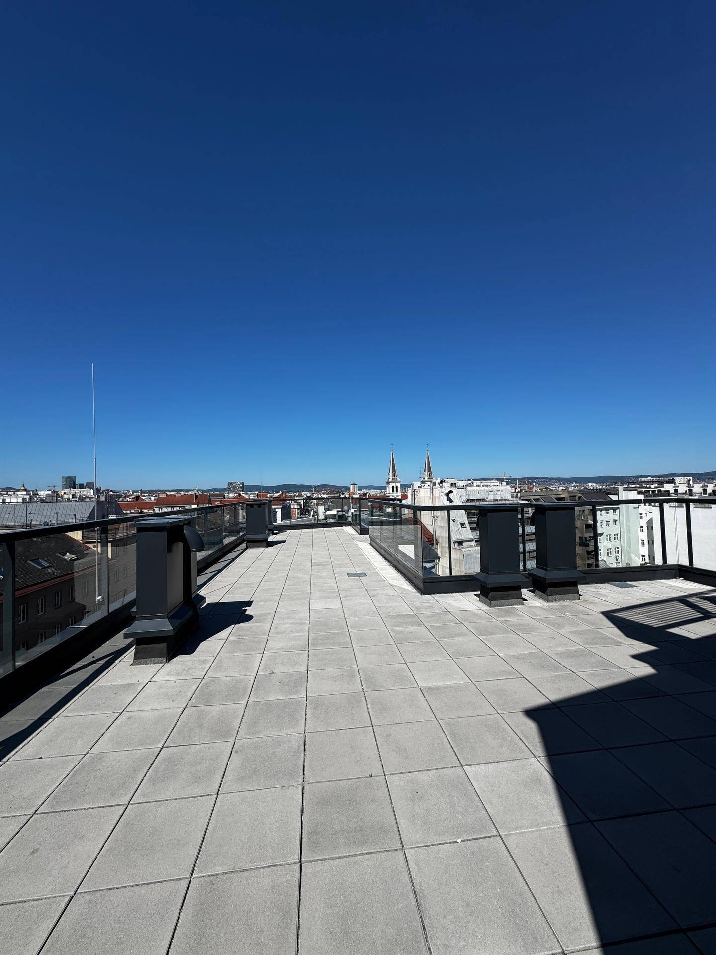 Geräumige Dachterrasse mit weitem Blick über die Stadt und umliegende Gebäude.