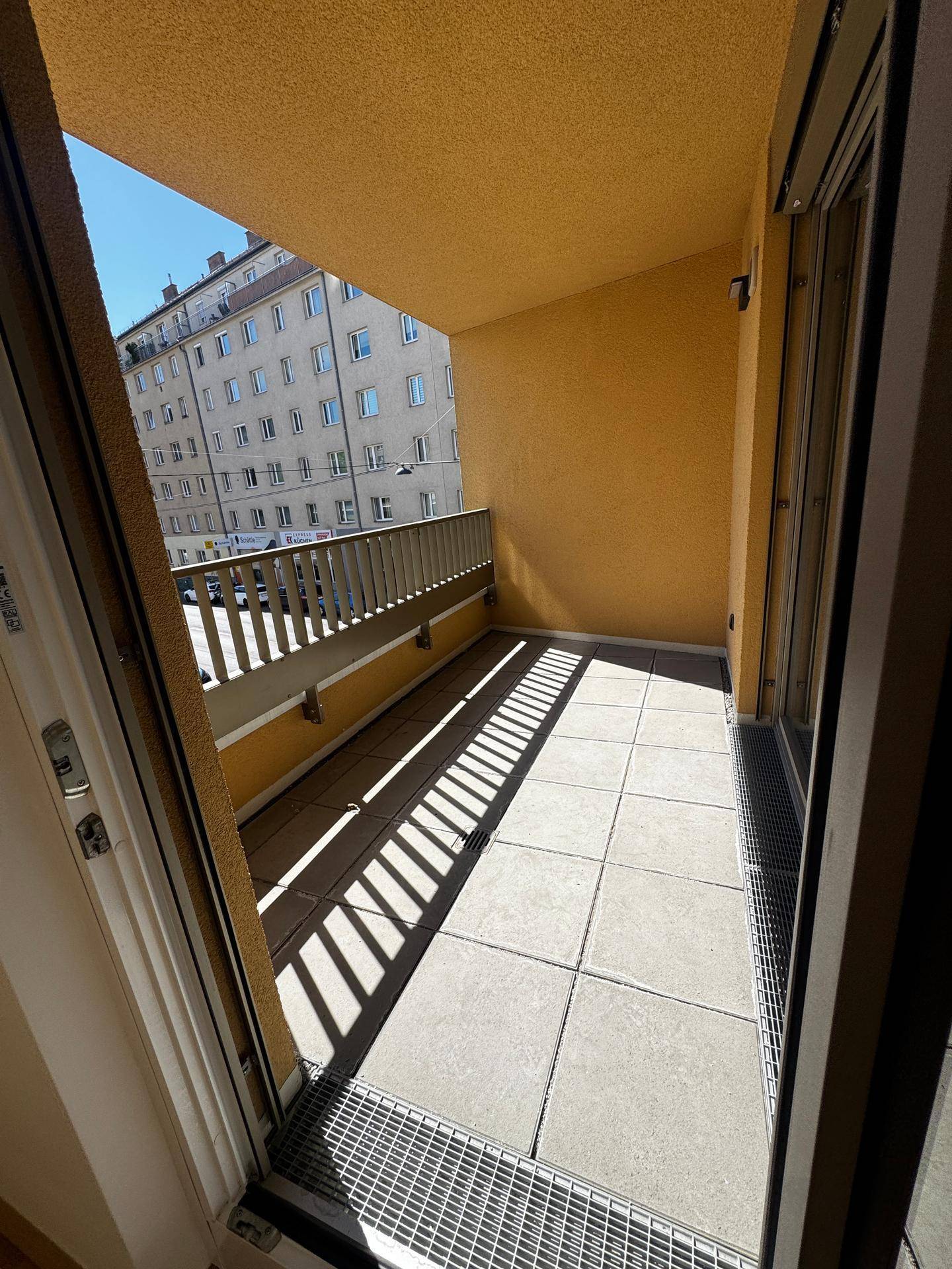 Überdachte Loggia mit Fliesenboden und Blick auf die umliegenden Gebäude.