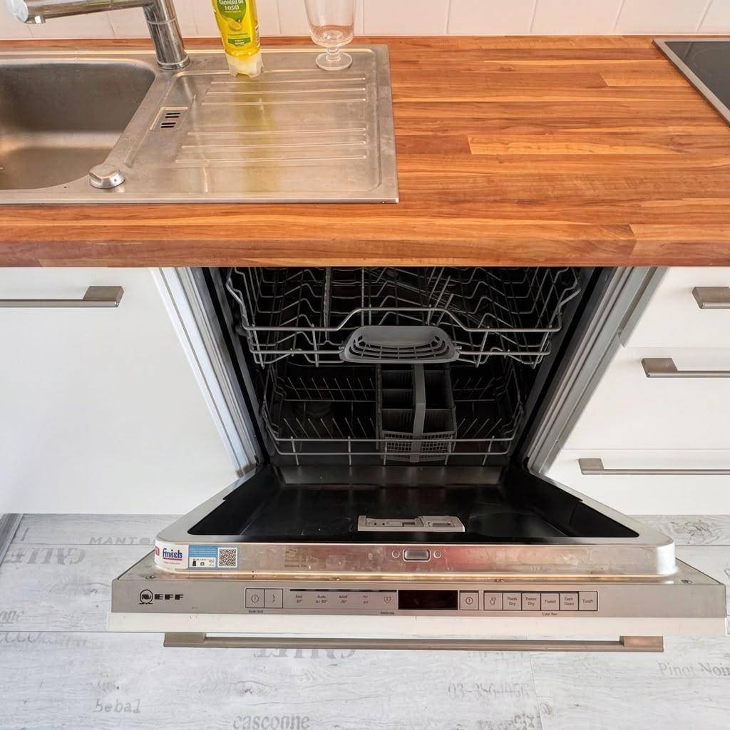 Integrierter Geschirrspüler in einer modernen Küche mit Holz-Arbeitsplatte und Edelstahlspüle.