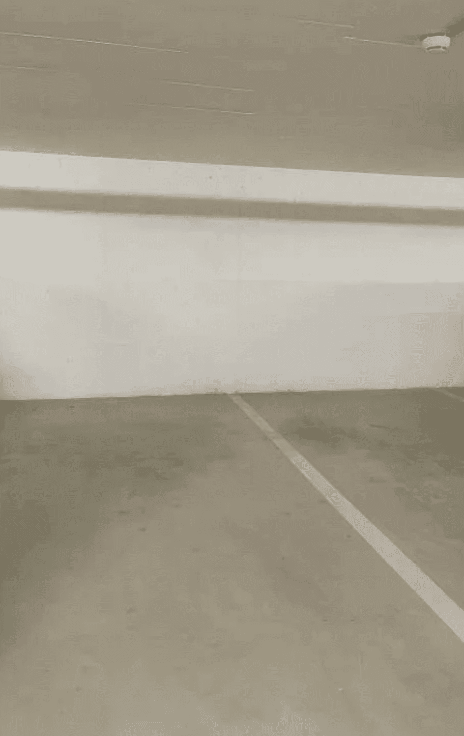 Leerer Parkplatz in einer Tiefgarage mit Betonboden und Markierungen.