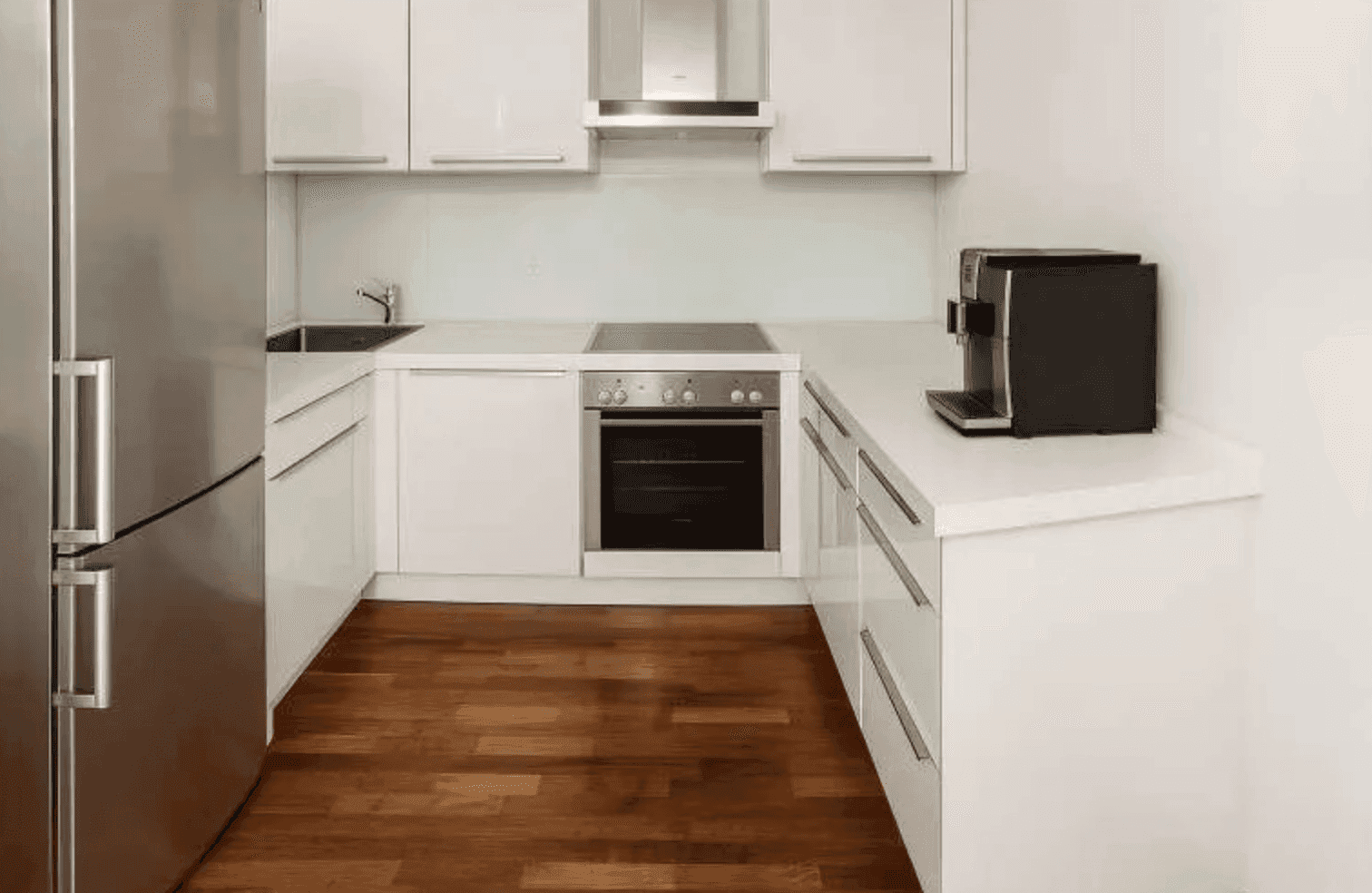 Moderne weiße Küche mit Hochglanzfronten, integrierten Geräten und Holzboden.