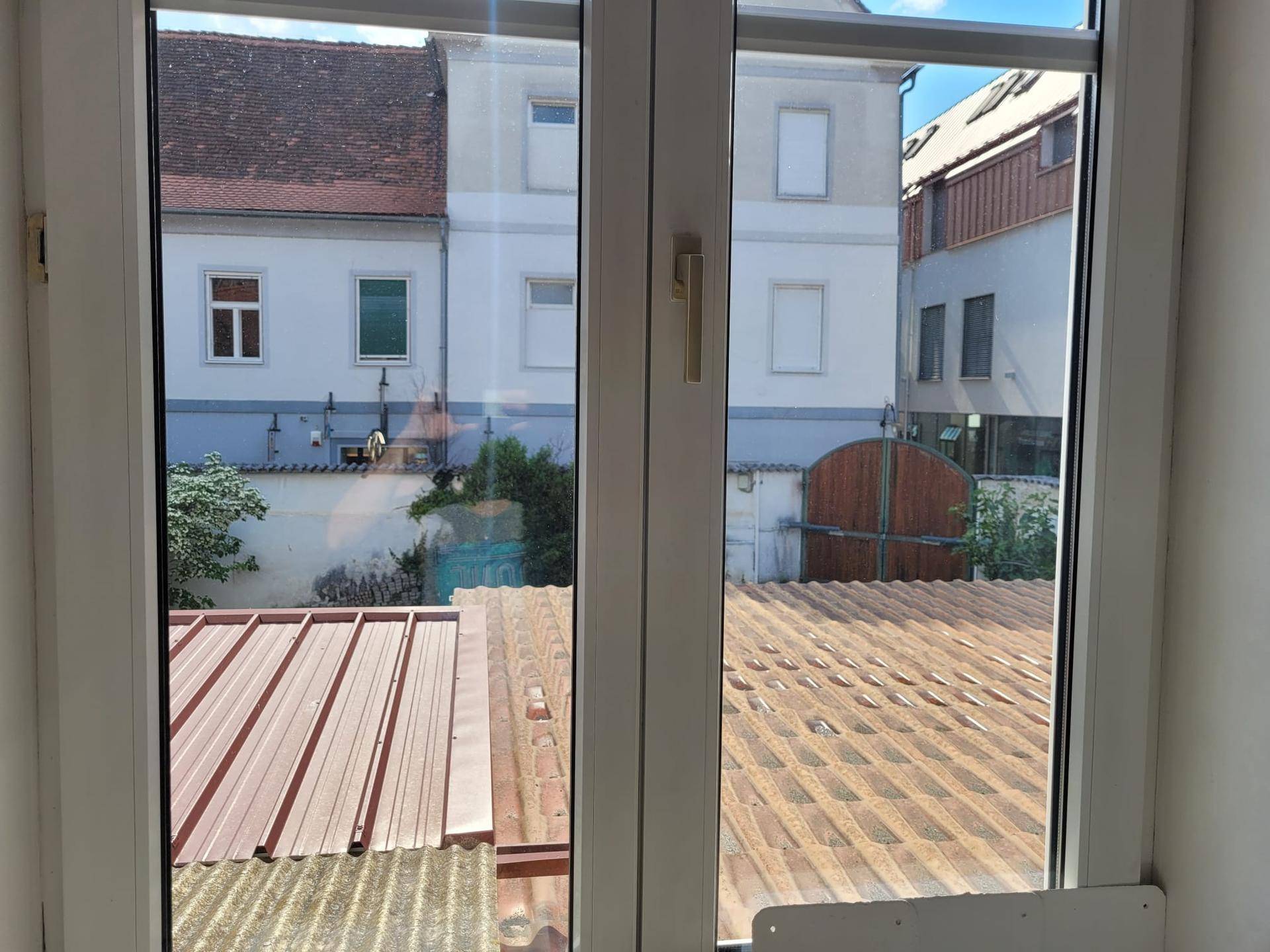Fensterblick auf die Dächer der Nachbargebäude und einen kleinen Innenhof.