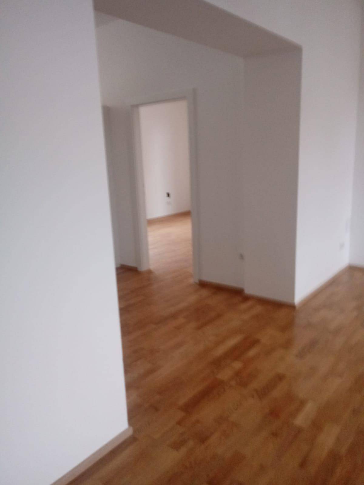 Heller Durchgangsbereich mit Holzparkettboden und weißen Wänden.