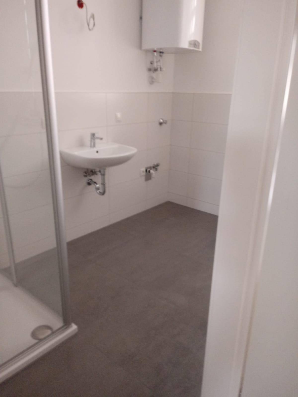 Modernes Badezimmer mit weiß gefliesten Wänden, Duschkabine und Waschbecken.
